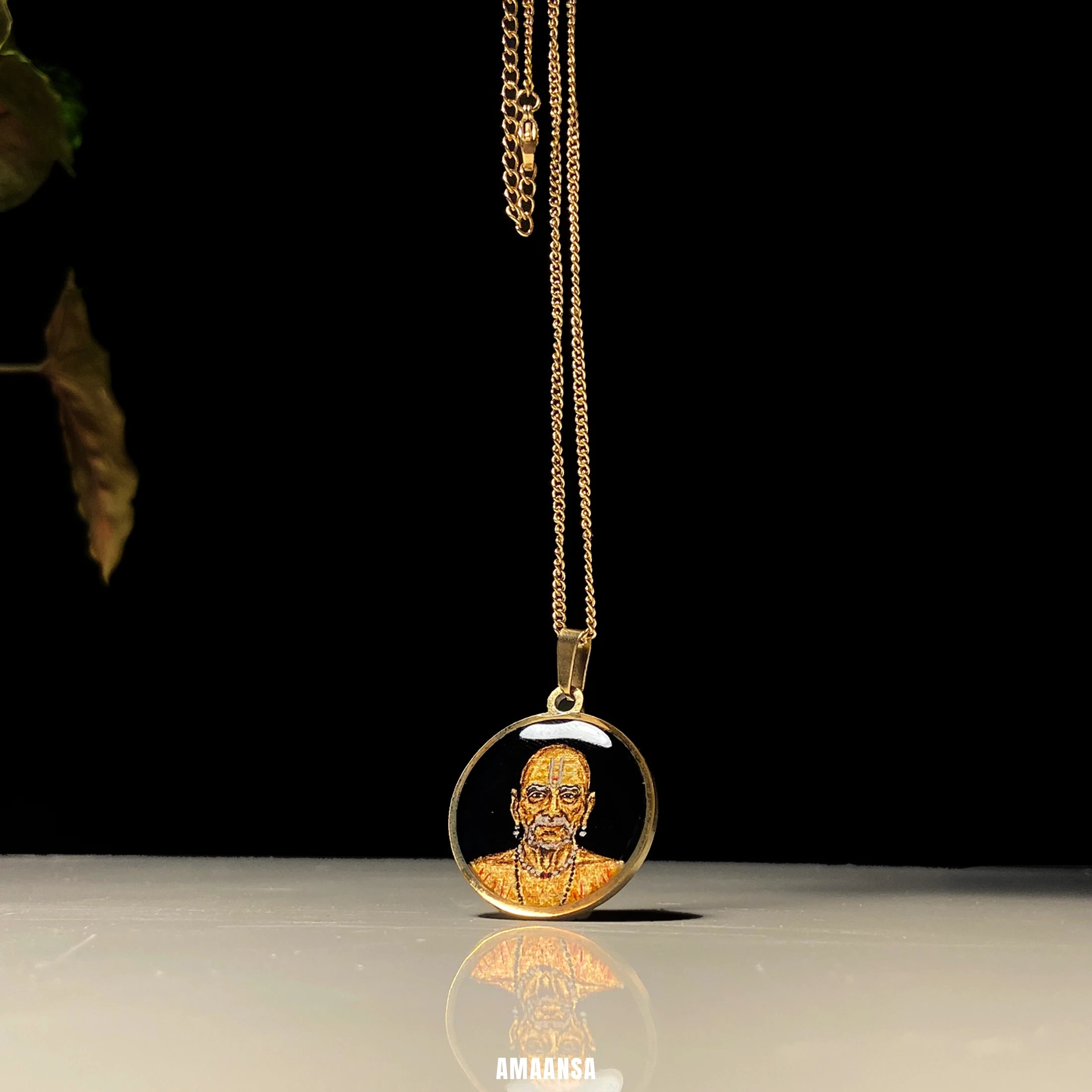 Side angle of Swami Samarth pendant lying on table, miniature portrait jewelry with gentle shadow, Gold necklace on a reflective surface.