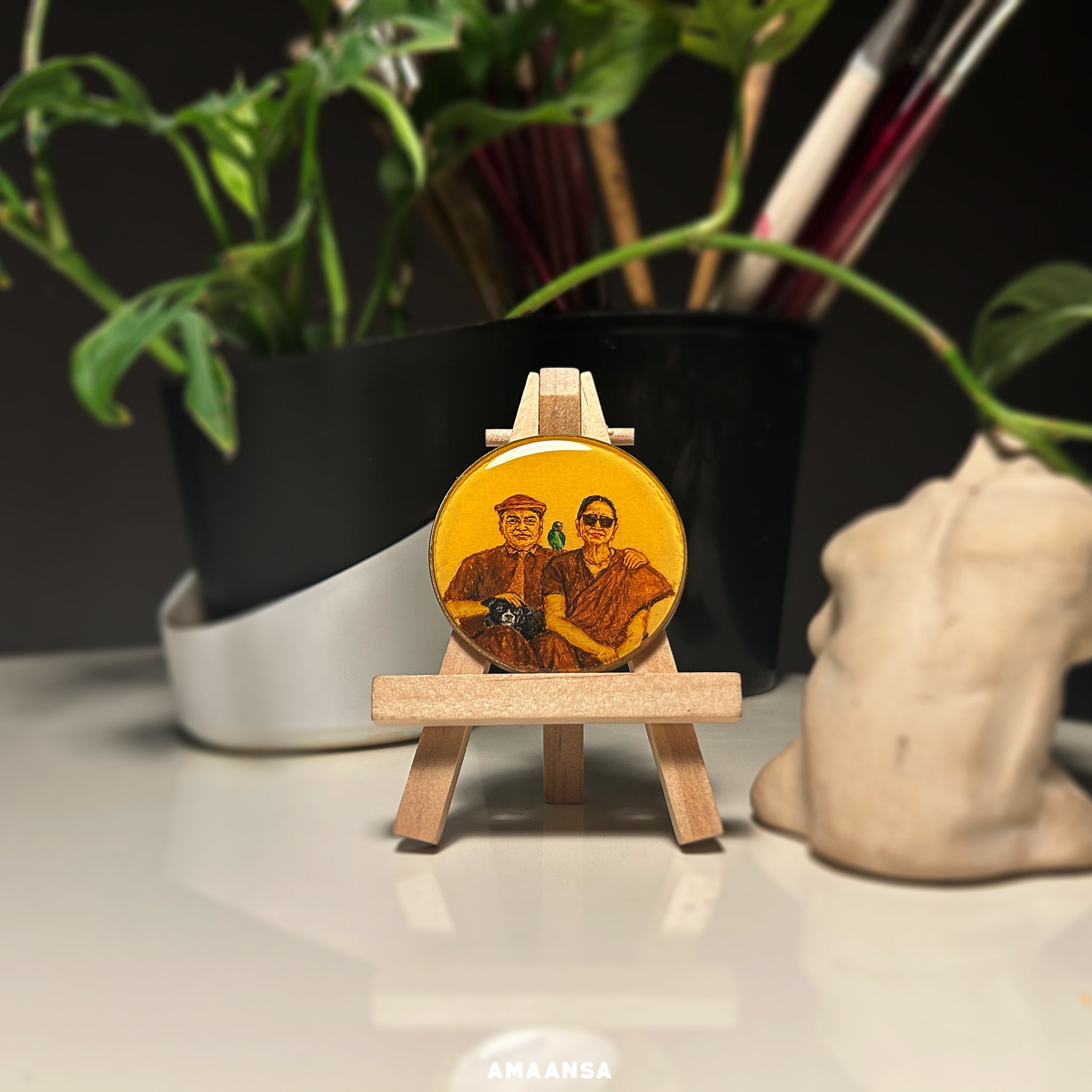 A 5cm diameter custom miniature painting featuring a client's great-grandparents and their pets, reflecting their love for animals. The grandfather, seated on the right, wears a European hat, shirt, and pants, with a black dog resting on his legs and a green parrot perched on his shoulder. The grandmother, on the left, wears a beautiful sari with stylish sunglasses. Set against a nostalgic theme, this handpainted tabletop showpiece from AMAANSA Fine Arts Studio captures intricate details and personal moment