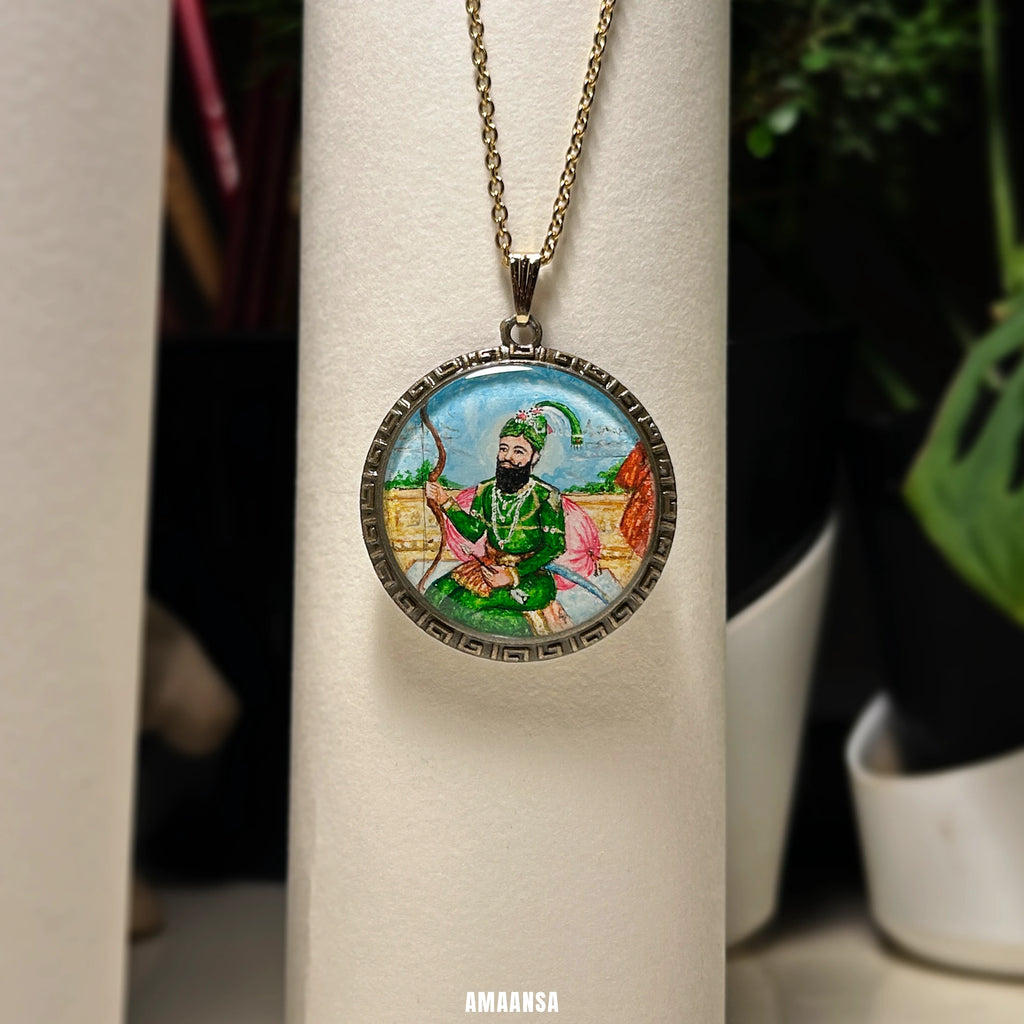 Close‑up of Guru Gobind Singh hand‑painted miniature pendant, vintage‑tone frame and green attire shown clearly for spiritual gift jewelry.