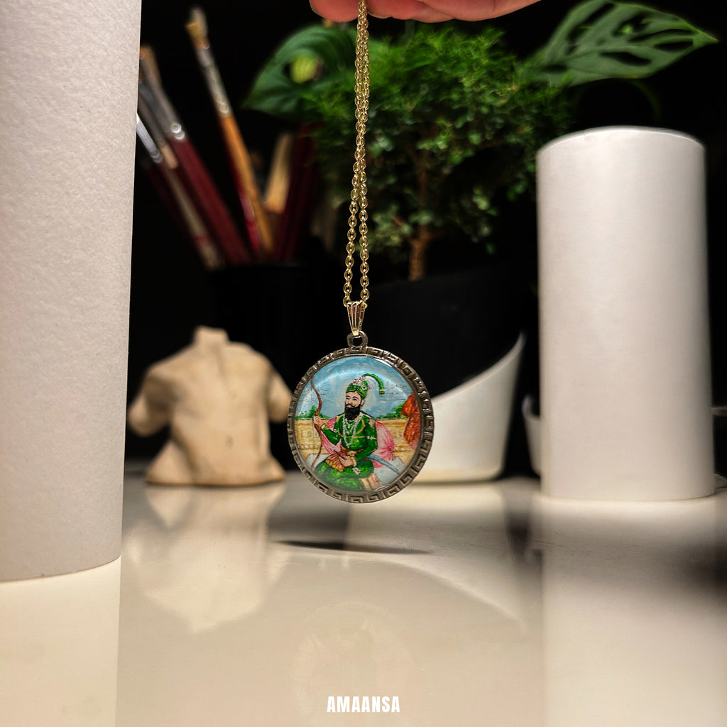Necklace with a pendant featuring a colorful depiction of a figure, held against a blurred indoor background.Guru Gobind Singh pendant full color handpainted miniature locket Sikh warrior deity jewelry Mughal Rajasthani style custom spiritual coin divine protection religious necklace devotional keepsake vintage base AMAANSA