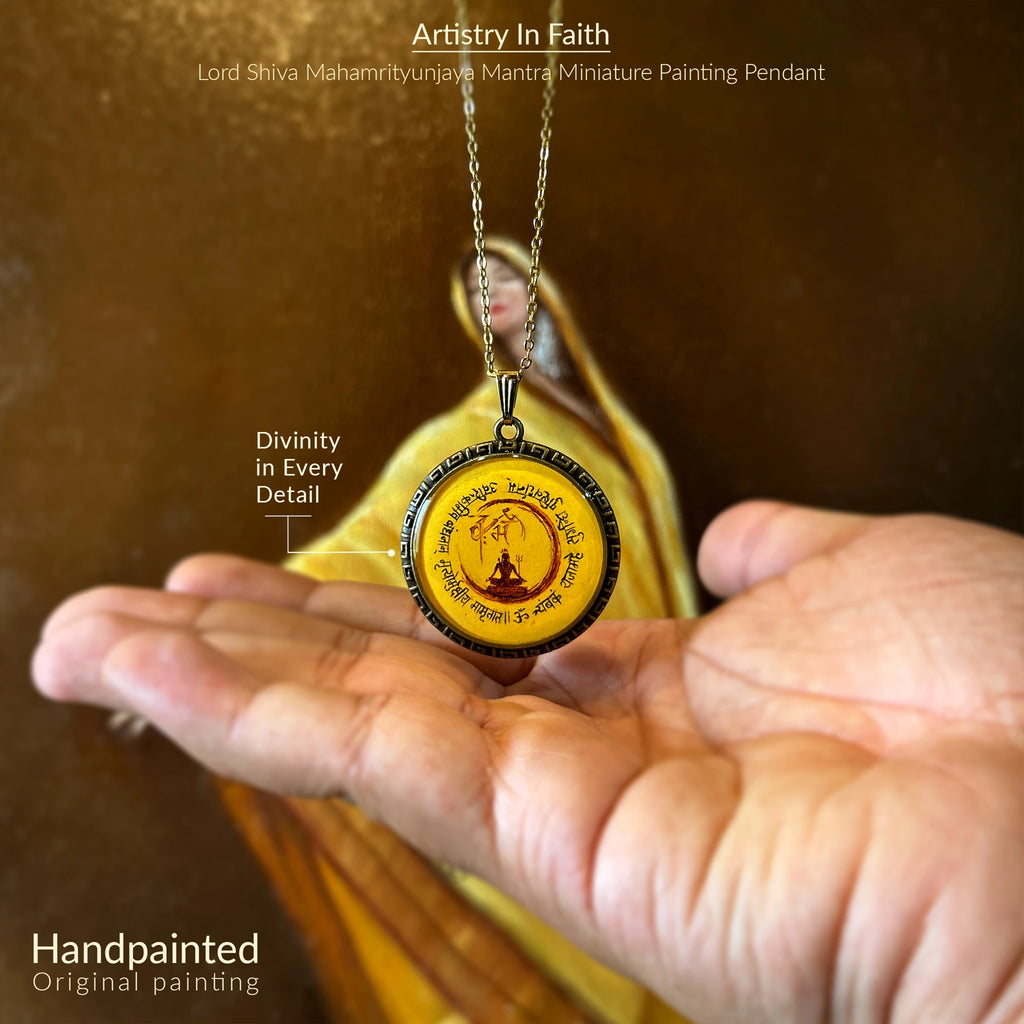 Handheld pendant with Lord Shiva Mahamrityunjaya Mantra Miniature Painting, held by a person against a blurred background.