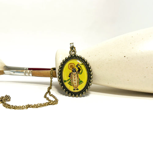 pendant with a antique metallic brass pendant featuring an painting of Shrinathji on a white surface, devotional Krishna necklace