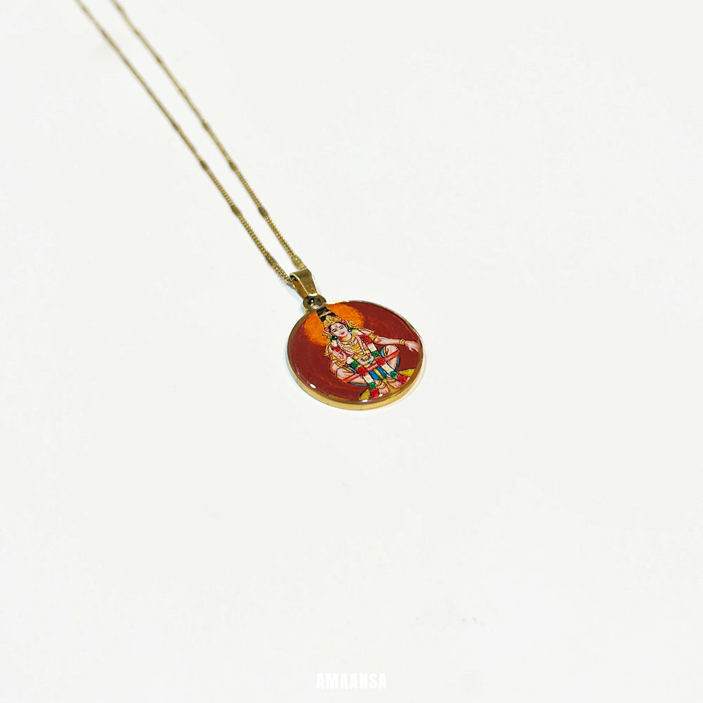 Round Lord Ayyappa handpainted pendant resting on glossy surface, spiritual jewelry with gold‑tone base.

