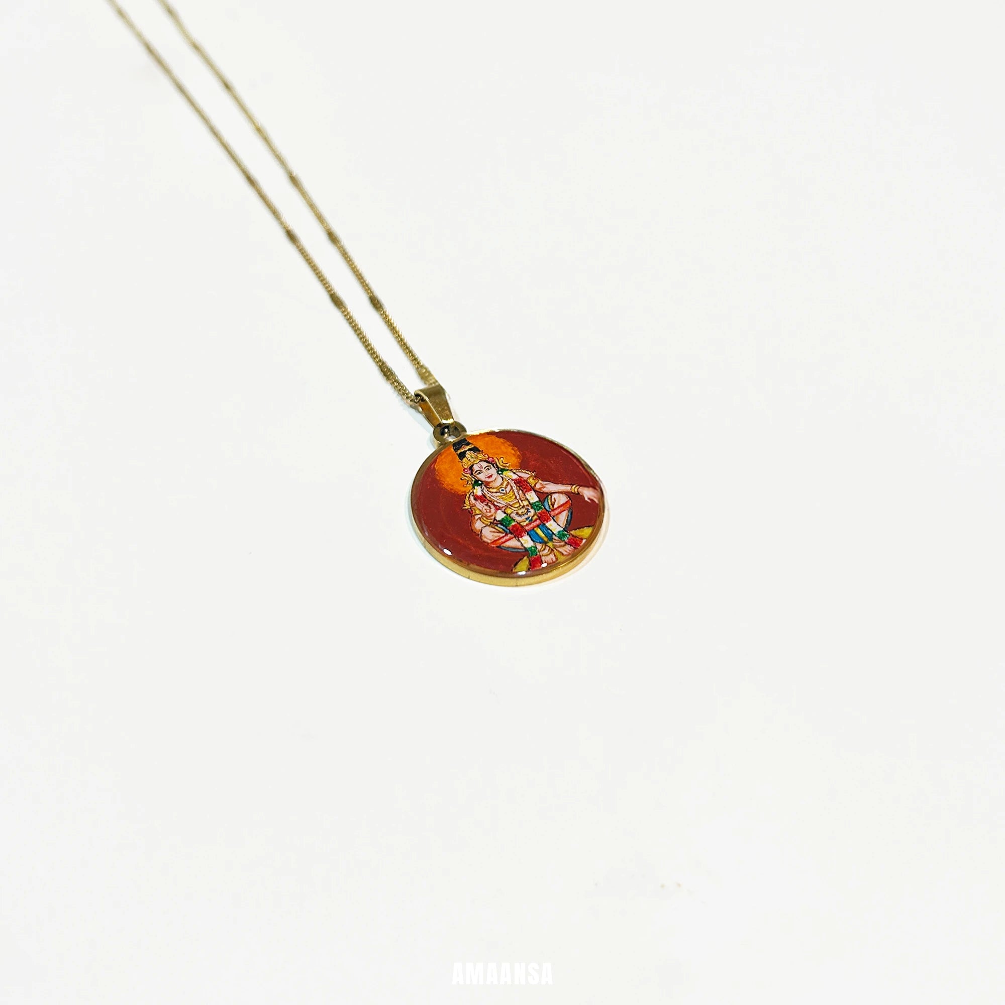 Round Lord Ayyappa handpainted pendant resting on glossy surface, spiritual jewelry with gold‑tone base.

