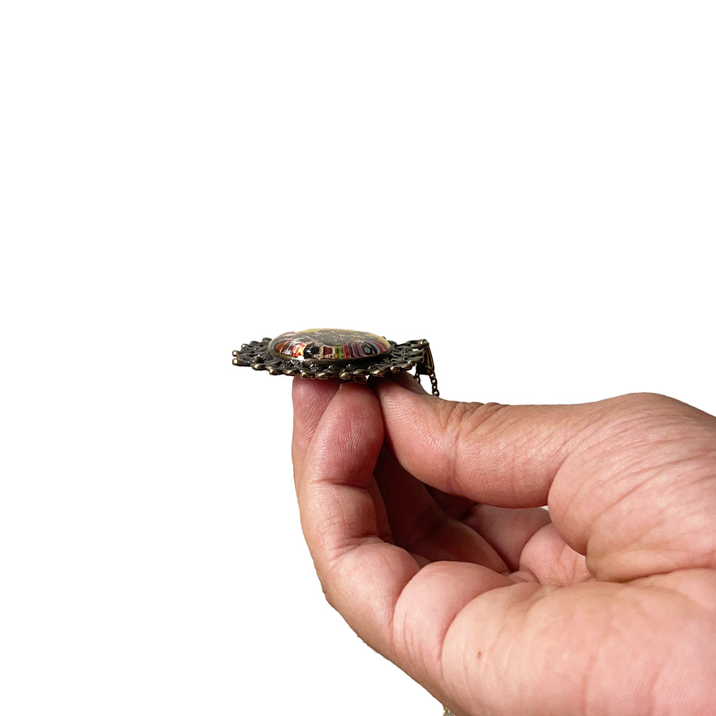 Banke Bihari pendant held between fingers, hand‑painted miniature worn as daily Vrindavan darshan.