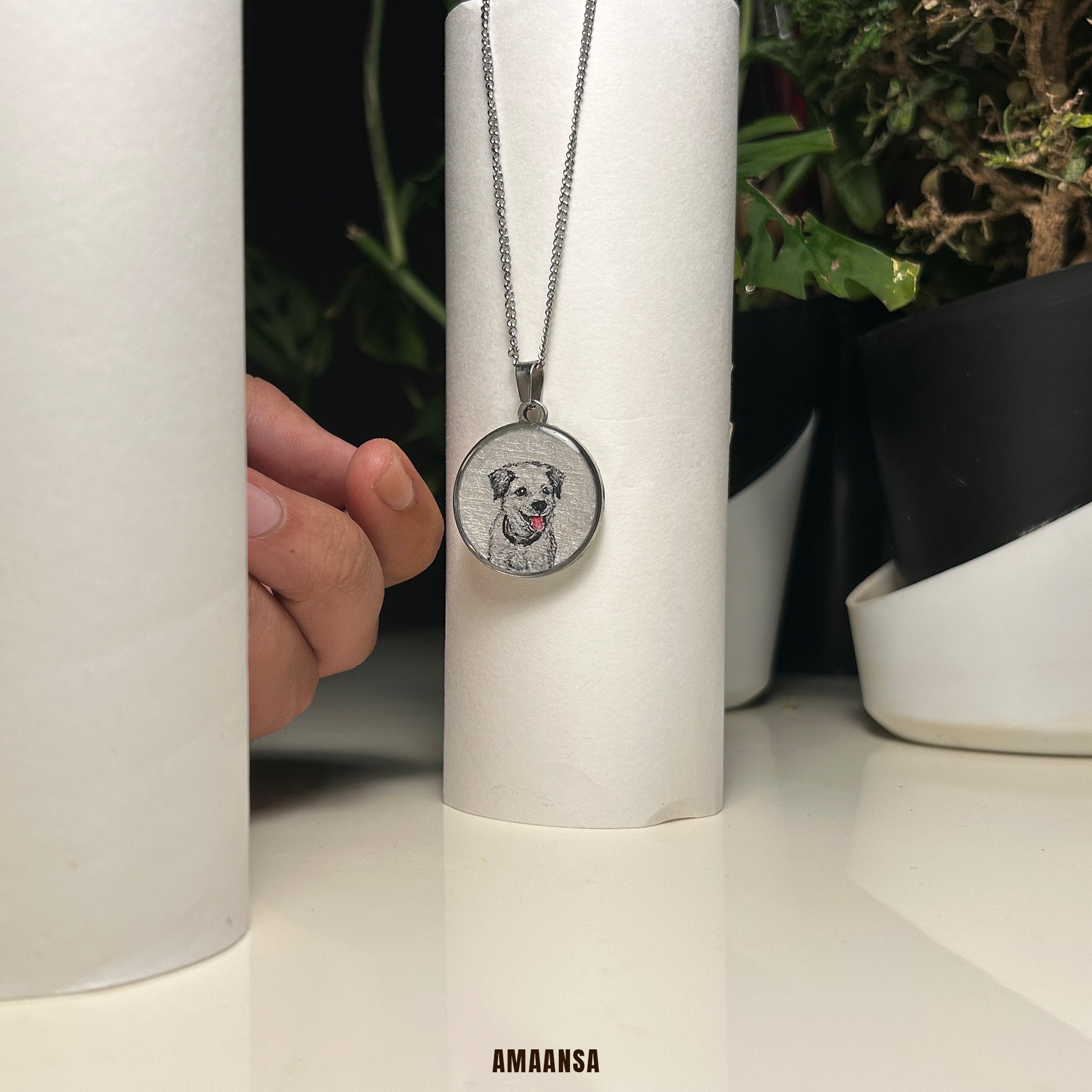 Necklace with a pendant featuring a dog's face on a white cylindrical object, with 'AMAANSA' branding. Handpainted Border Collie portrait necklace premium silver finish pet memorial jewelry custom dog pendant miniature art pet keepsake personalized tribute commissioned memorial locket furry companion heirloom collectible