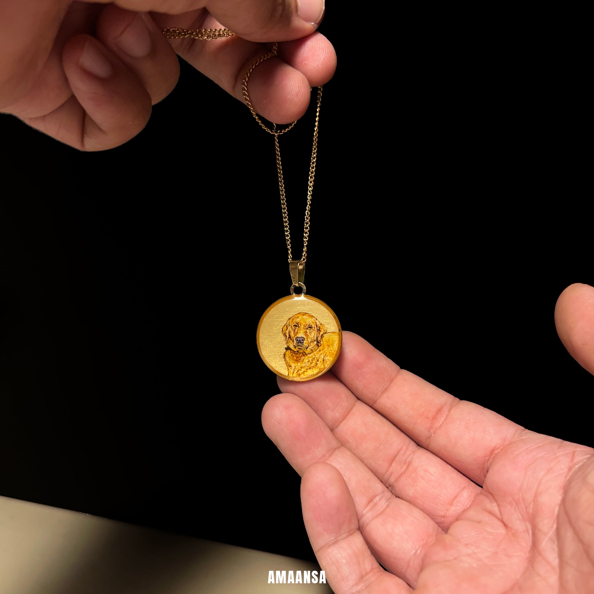 Gold pendant with a dog's face on a chain held by hands against a black background. Custom Golden Retriever memorial pendant handpainted miniature portrait 18k gold PVD premium pet jewelry dog memorial locket personalized keepsake commissioned pet tribute wearable nostalgia AMAANSA artistry furry family treasure
