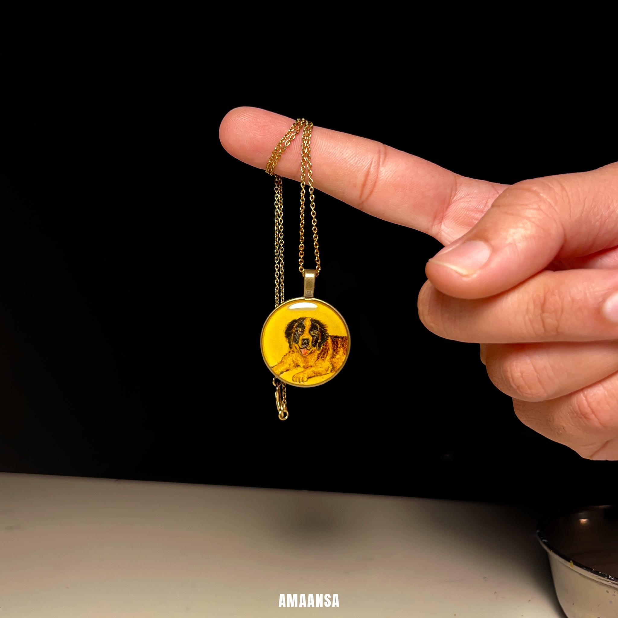 Hand holding a gold plated necklace with a round pendant featuring a dog's face against a black background. Vintage style pet memorial pendant handpainted Australian Shepherd miniature portrait antique patina chain custom dog jewelry vintage yellow background personalized keepsake furry companion remembrance AMAANSA artistry collectible locket