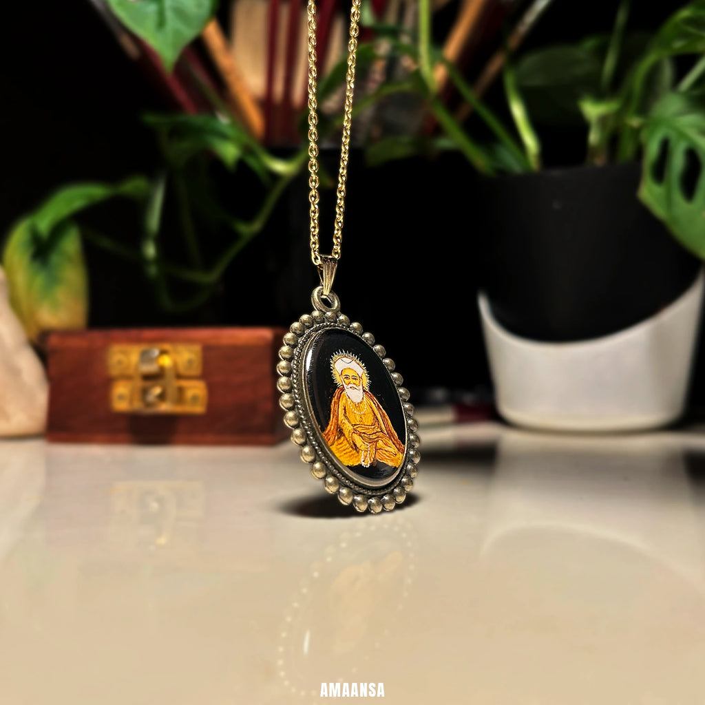Side view of Guru Nanak pendant lying on surface, devotional necklace casting soft reflection with plants in the background