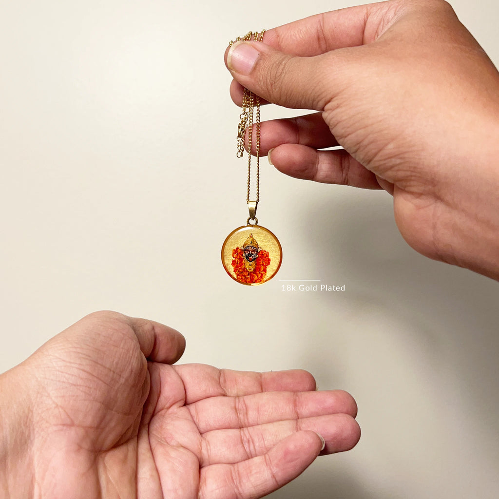 Close‑up of Maa Kali hand‑painted miniature in 18k gold‑plated gold‑tone beaded frame, devotional pendant hanging against light background.