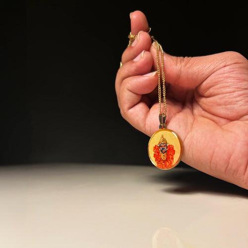 Hand holding a Maa Kali 18k gold‑plated miniature portrait pendant on chain, gold‑tone frame hanging from hand surface for spiritual jewelry display
against a dark background