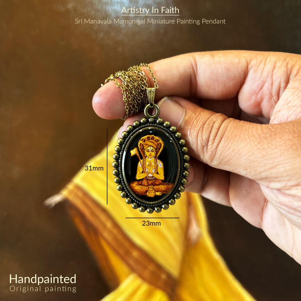 AMAANSA Fine Arts Studio presents: Devotional oval pendant (31x23mm) featuring Sri Manavala Mamunigal's complete portrait. His serene meditation posture and traditional attire rendered in rich golden hues, embraced by our Vintage Pearl Border design. Antique gold colored chain gracefully suspended, pendant held between fingers against warm backdrop. Sealed with protective finish, this sacred art piece honors spiritual legacy.
