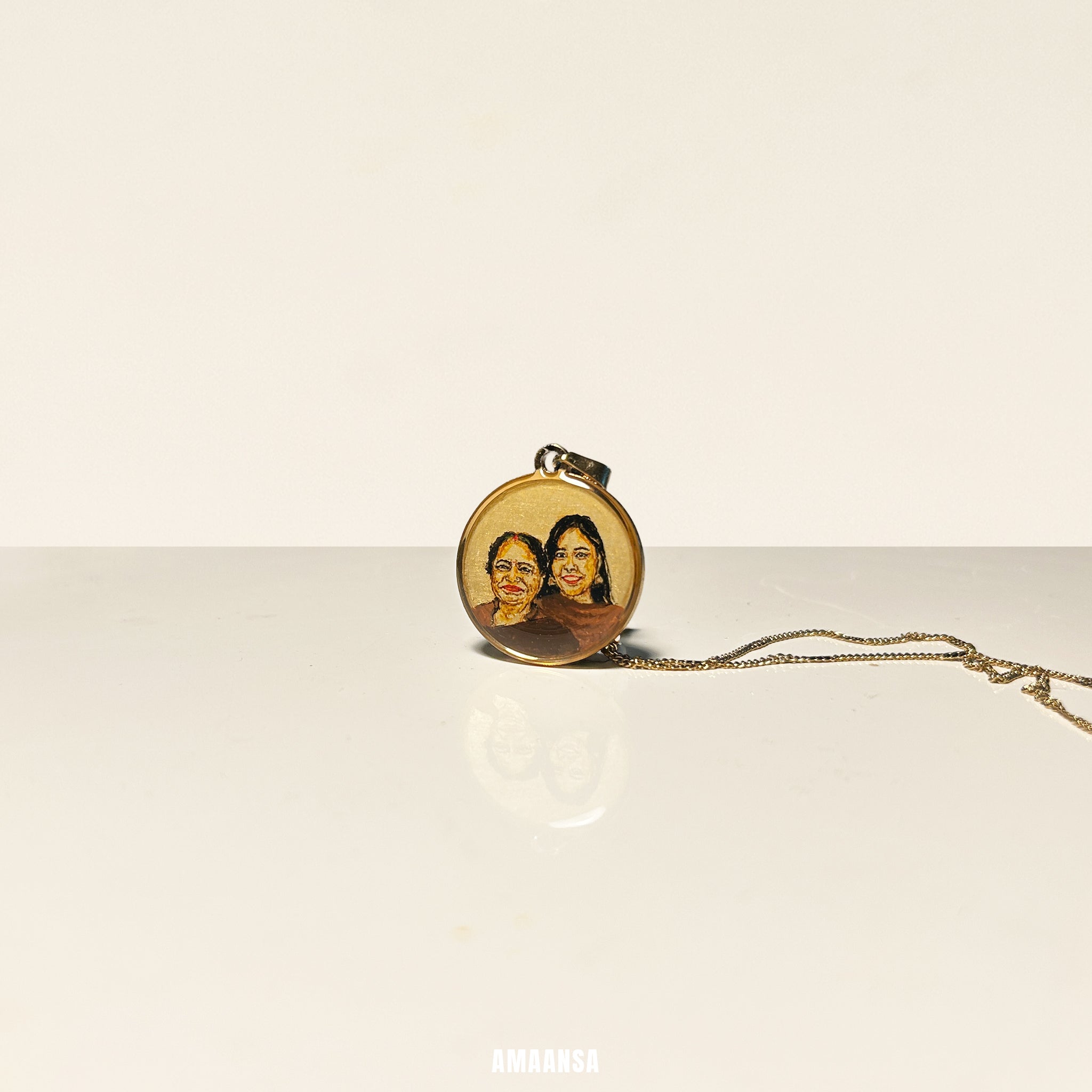 Gold necklace with a pendant featuring two women's portraits on a beige background. Custom 18k gold PVD two face pendant daughter late mother handpainted miniature art engagement gift sister commissioned luxury jewelry burnt umber painting stainless steel AMAANSA memorial treasure presence