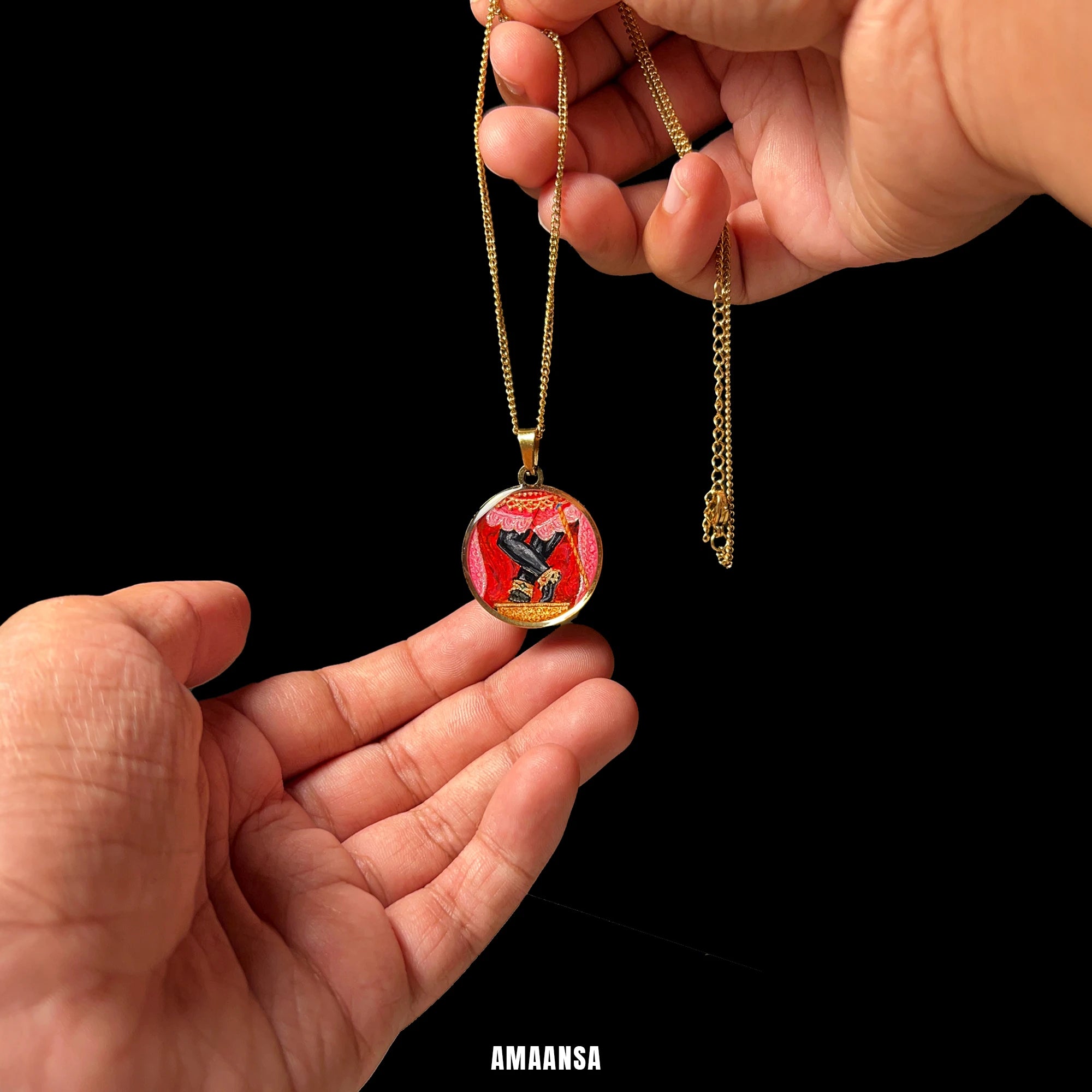 Round 18k gold‑plated Sri Radharamanji paduka pendant on chain, devotional necklace centred and held by hands against a black background.