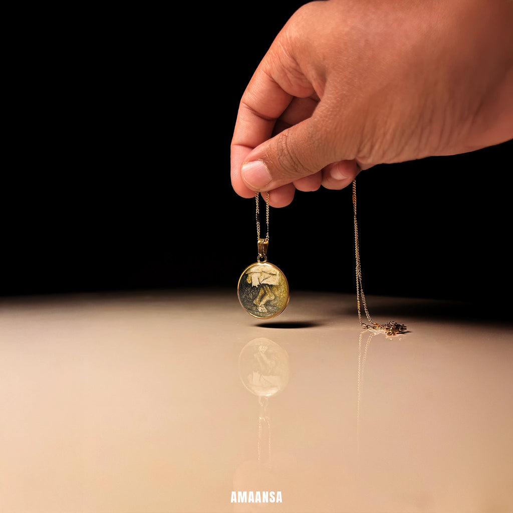 Hand holding a Sai Baba charan 18k gold‑plated round pendant on chain, devotional necklace photographed in warm studio light on a reflective surface