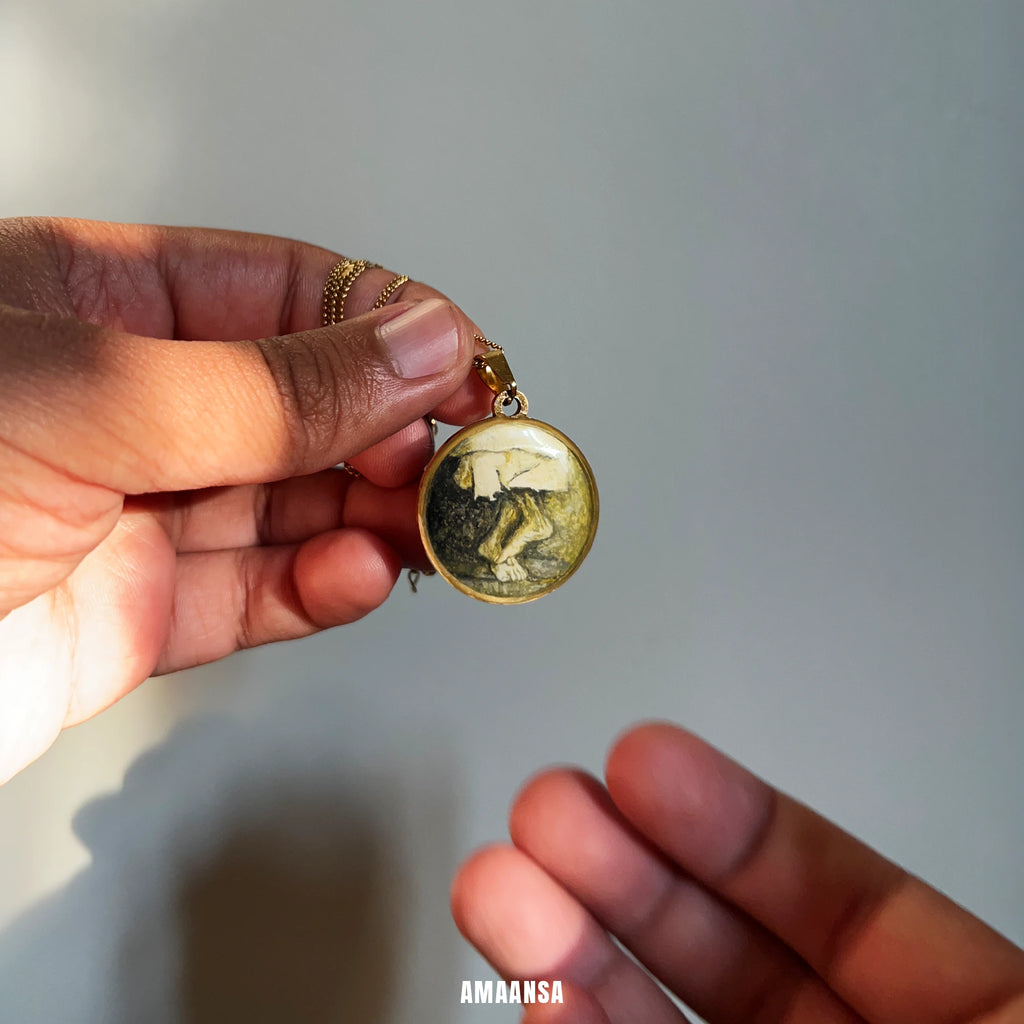 Hand holding a round pendant with a painting of Sai Charan (feet) against a neutral background
