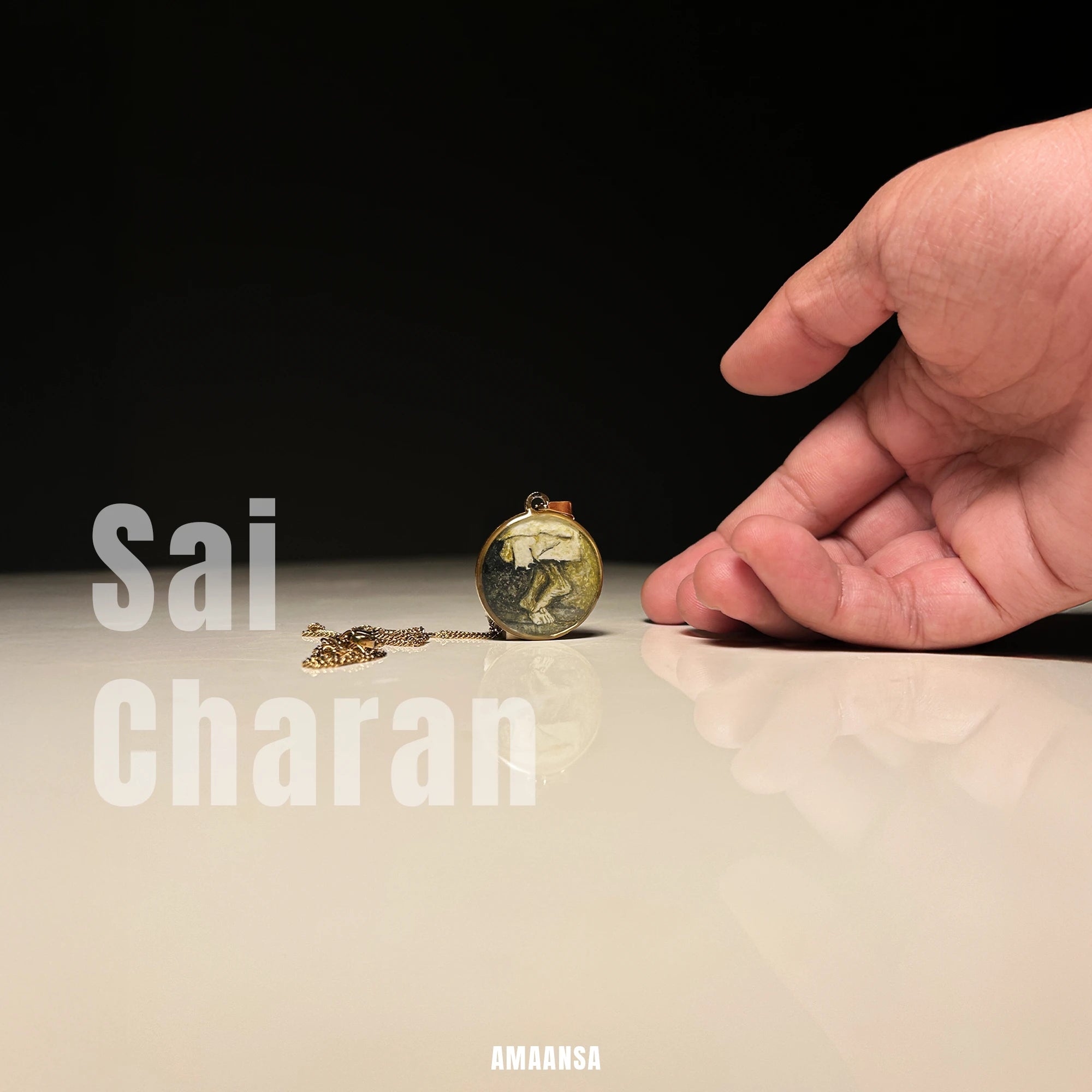 Hand reaching towards a Sai Baba charan 18k gold‑plated pendant standing upright on glossy surface on a reflective surface with 'Sai Charan' text.