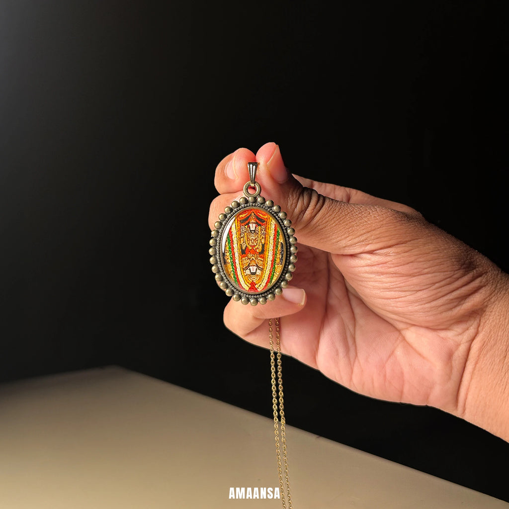 Sri Dwaraka Tirumala Venkateswara Swamy hand‑painted miniature pendant in antique gold‑tone oval frame on chain, devotional necklace on soft surface against a black background