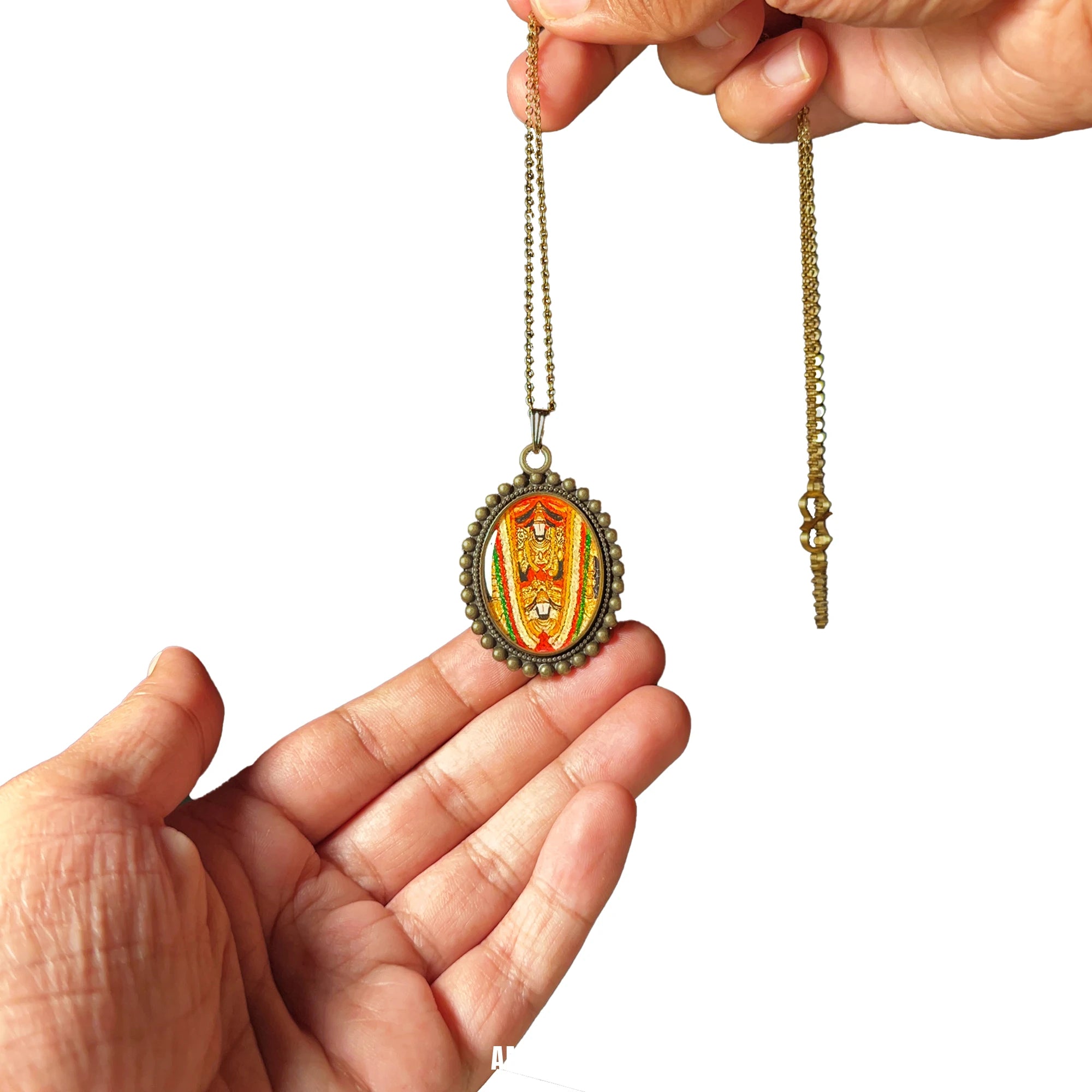Hand holding Sri Venkateswara Swamy antique gold‑tone oval miniature pendant on chain, devotional necklace shown as spiritual gift.