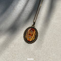 Sri Dwaraka Tirumala Venkateswara Swamy gold‑tone oval miniature pendant on chain on a textured gray background,.