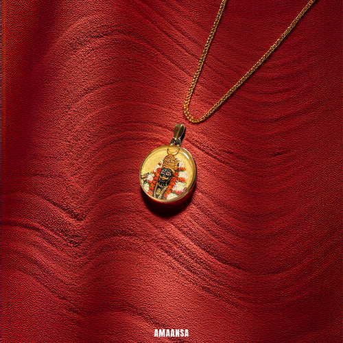 Gold pendant with a religious figure on a red fine grain sand. Custom 18k gold PVD locket handpainted Kala Bhairava half-body miniature art semicolor pendant red-orange garland white flowers devotional jewelry divine protection religious keepsake wearer blessing