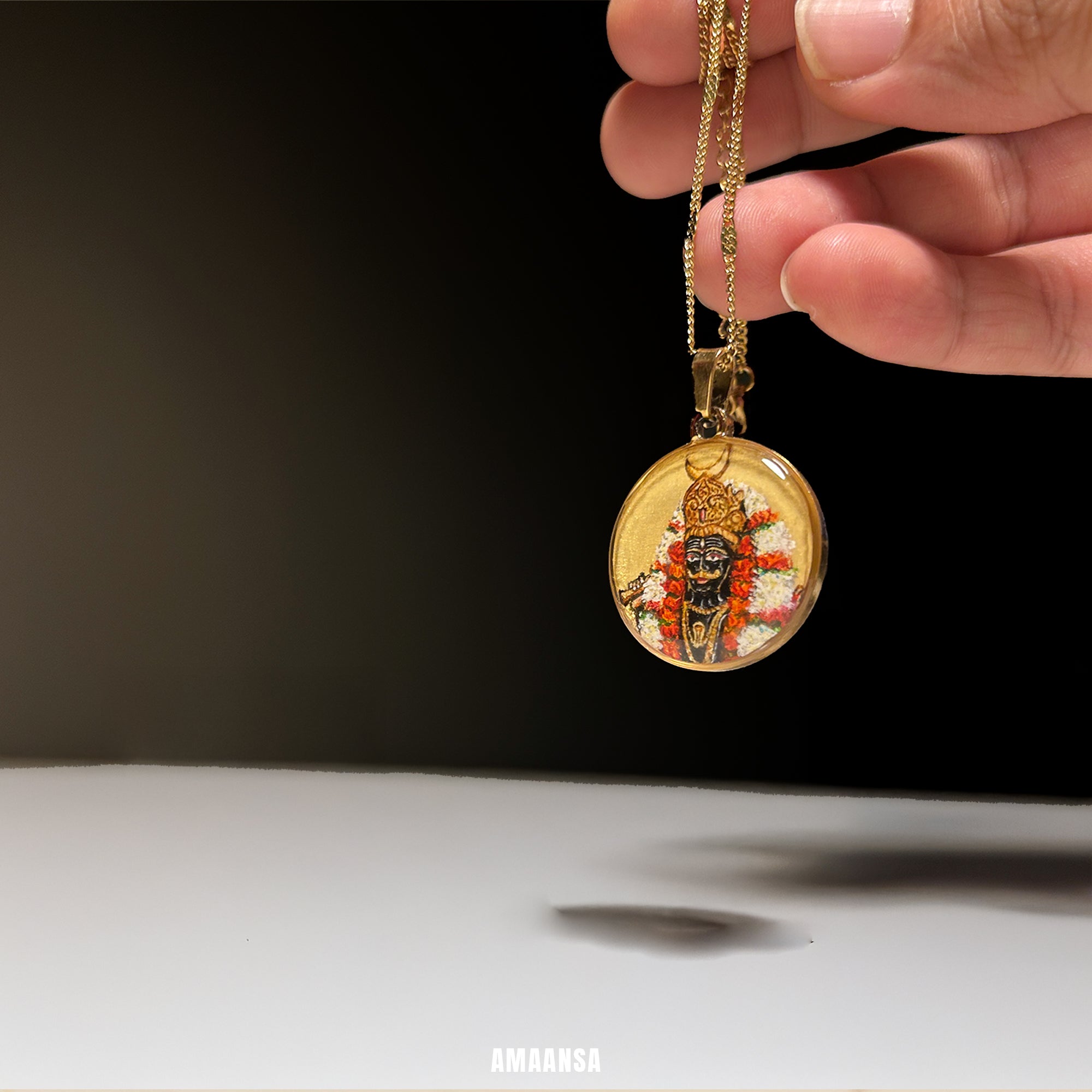 Gold pendant with intricate design held by a hand against a black background. Custom deity locket Shmashana Adhipati half-body miniature painting semicolor 18k gold PVD pendant white and red garland devotional jewelry religious keepsake protective amulet collectible