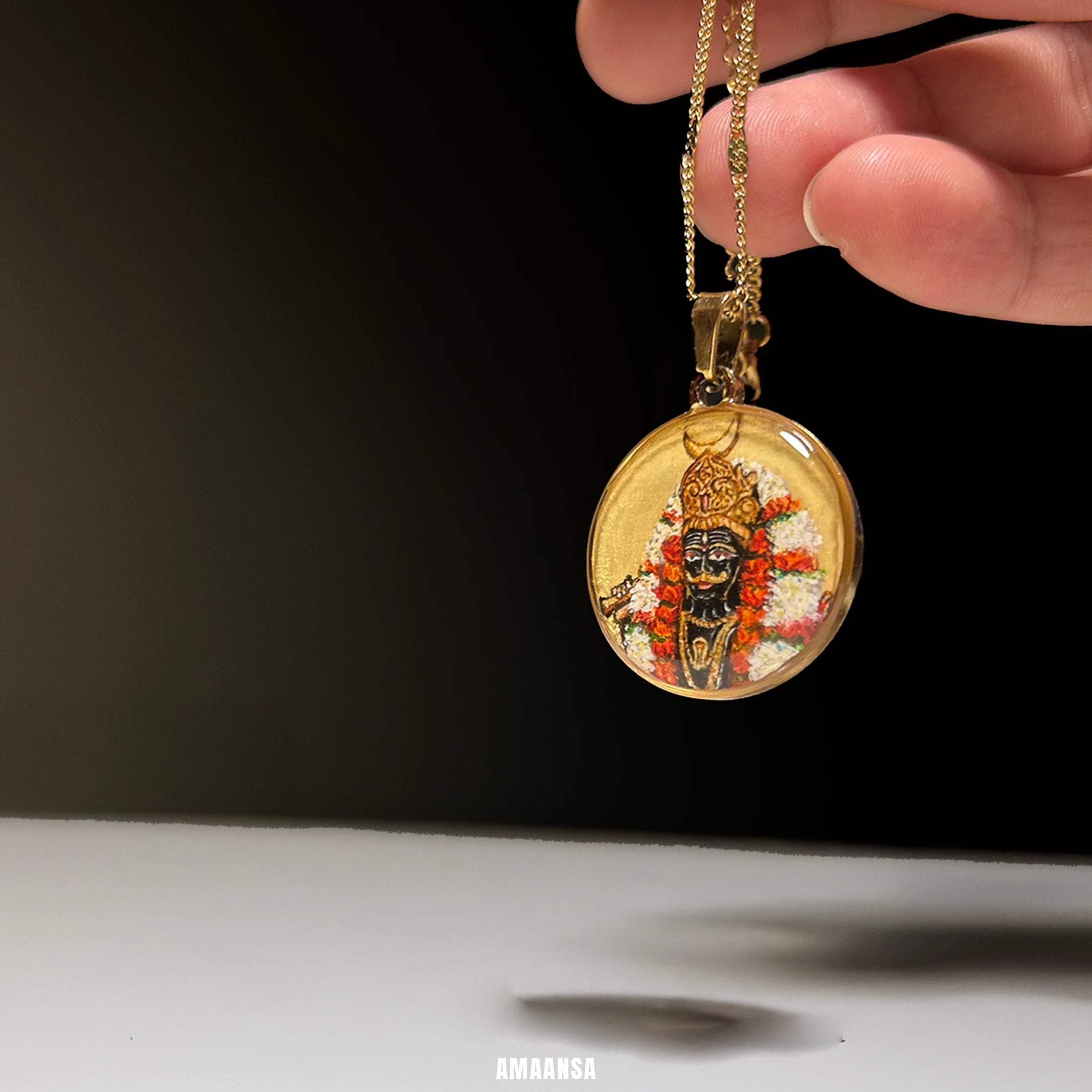 Side view of Kaal Bhairava 18k gold‑plated pendant lying on red textured fabric, hand‑painted miniature temple jewelry for protection.