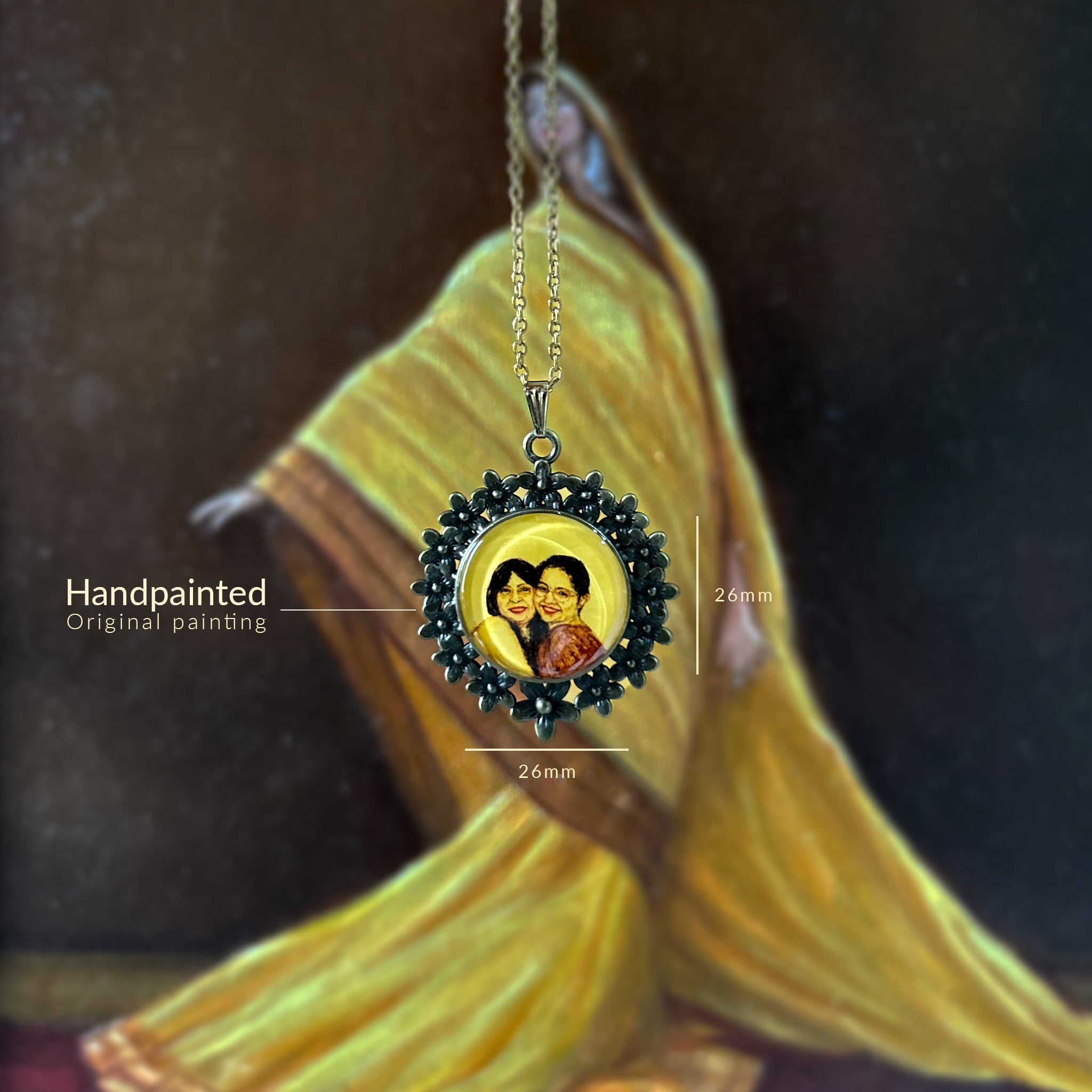 Handcrafted miniature painting transformed into memorial pendant (26mm): daughter and late mother's radiant smiles captured in intimate portrait, each brushstroke on naples yellow celebrating maternal strength. Delicate painted keepsake framed by ornate floral border, this wearable art piece suspended against artist's oil painting, preserving cherished moments beneath crystal-clear finish.