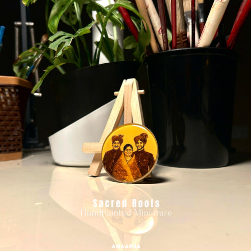 AMAANSA's heritage tribute in 50mm handpainted miniature - capturing regal lineage of Chhatrapati Shivaji Maharaj's descendants in traditional Dussehra ceremonial attire, father and son adorned in distinctive turbans and royal garments flanking mother in graceful saree, their noble bearing meticulously rendered by artist Abhinav in rich sepia and burnt umber against luminous vintage yellow backdrop, displayed on wooden easel amid artist's studio with monstera leaves