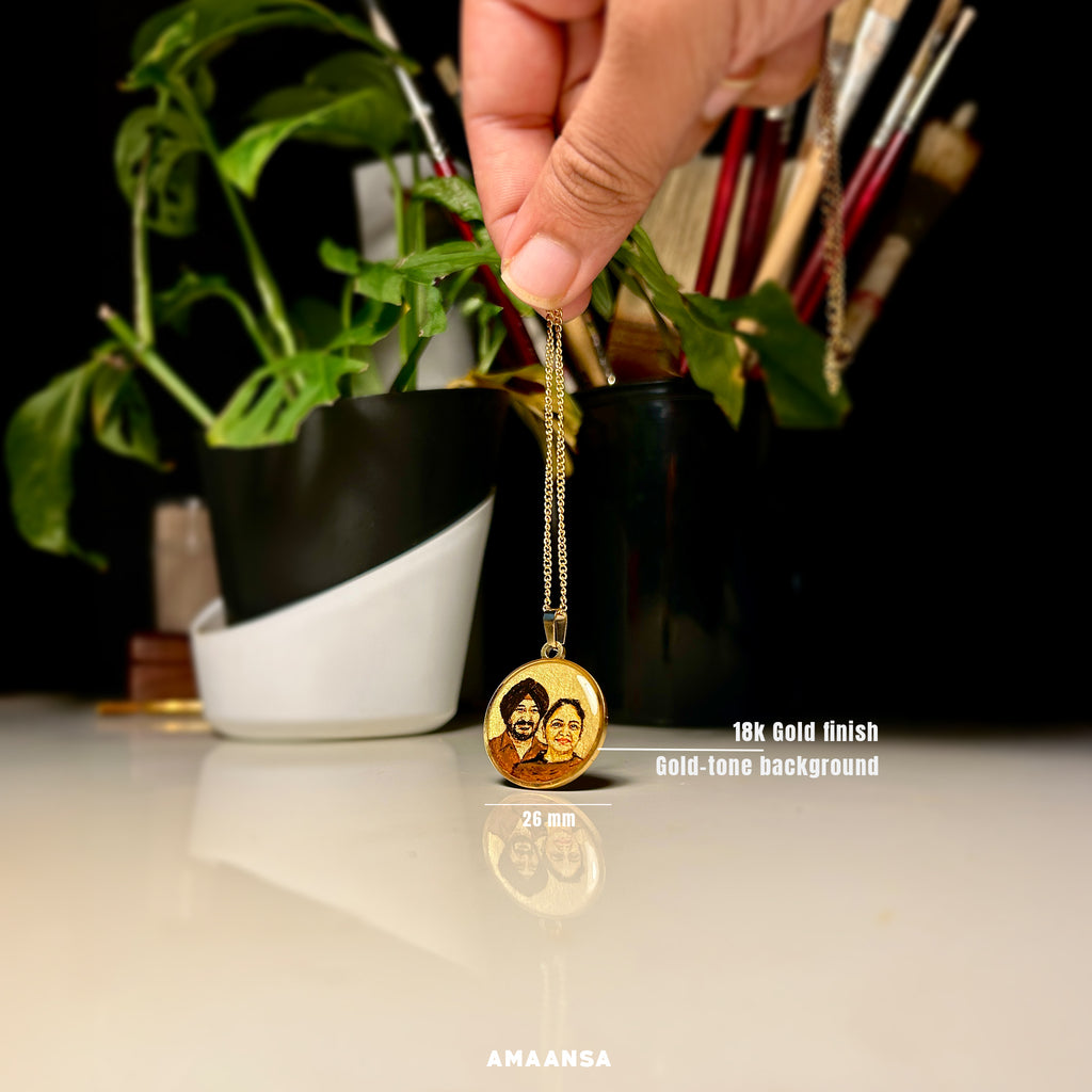 Bespoke miniature artistry merges cherished memories - 26mm pendant showcasing parents' united portrait crafted from separate photographs, father's distinguished turban and gentle smile beside mother's radiant expression, expertly harmonized by artist Abhinav in rich sepia tones against luminous gold backdrop, elegantly suspended from 18k gold PVD plated chain held against vibrant monstera leaves, reflecting the pendant's delicate scale