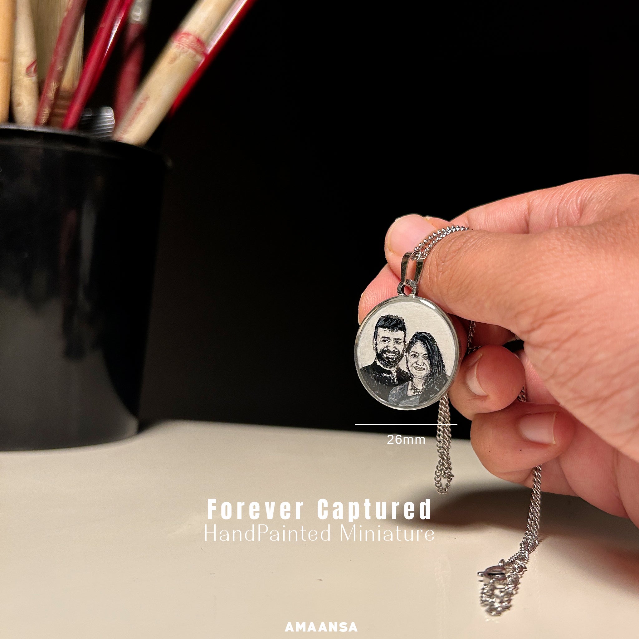 Handcrafted celebration of matrimonial bliss in 26mm miniature - transforming cherished wedding memory into elegant keepsake, capturing couple's natural chemistry with detailed precision - from his expressive smile to her gentle glow, meticulously painted in silver-toned palette by artist Abhinav, housed in rhodium-colored setting, scale artistically demonstrated with gentle hand hold amid studio setting