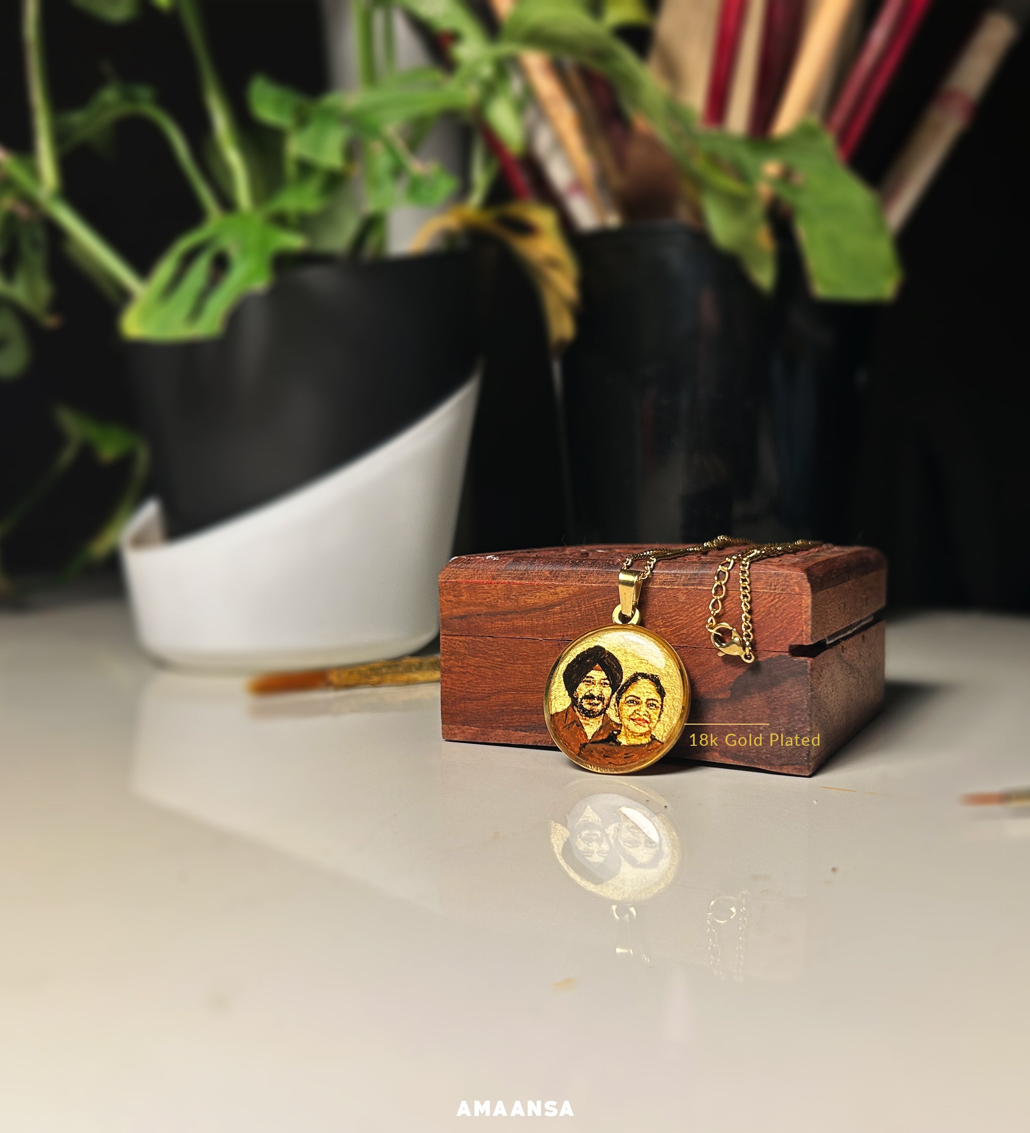 Bespoke miniature artistry merging cherished memories - daughter's commissioned 26mm tribute combining two treasured photographs, each detail lovingly preserved from father's traditional turban to mother's radiant presence, meticulously handpainted at AMAANSA's studio in warm sepia against vintage gold, 18k gold PVD plated setting complementing carved wooden trinket box, creating an heirloom that bridges past and present