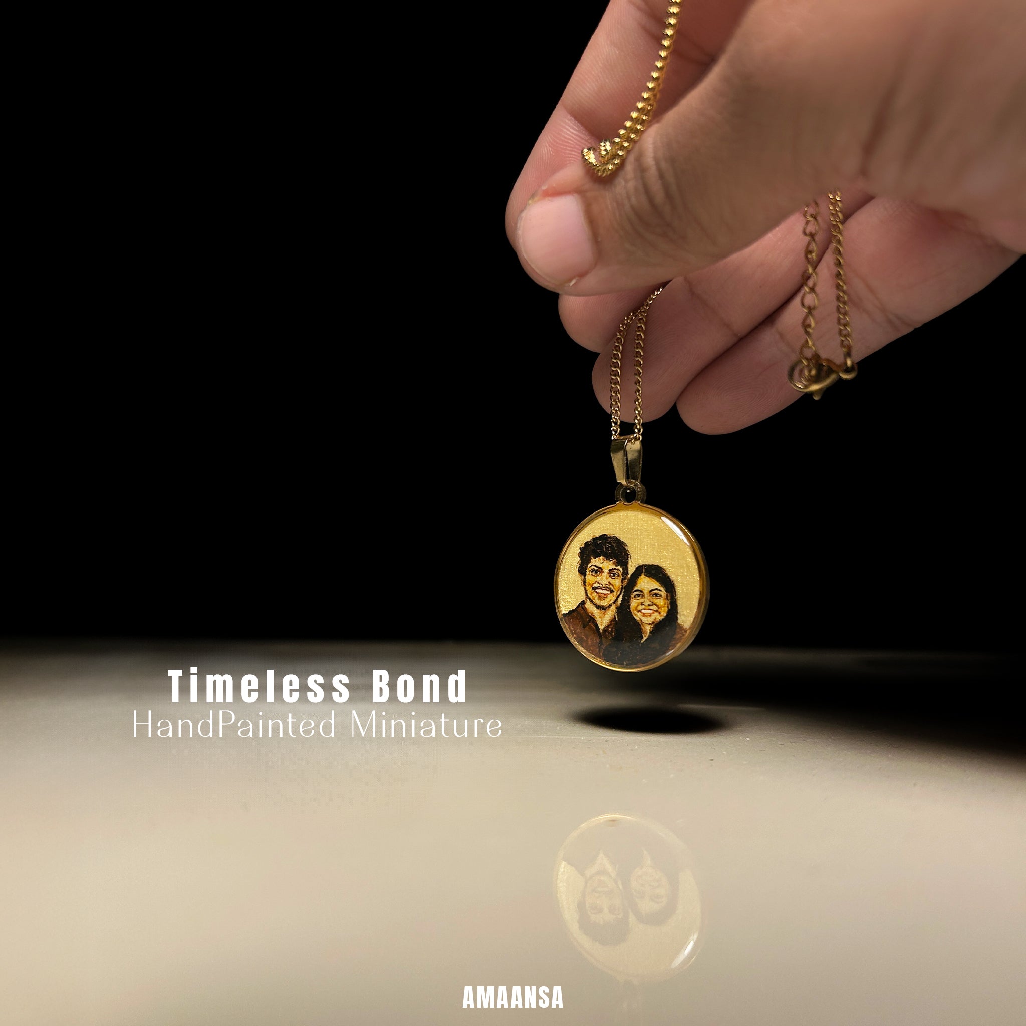 18k Gold plated pendant with a hand-painted miniature of two people, held by a hand against a black background.
