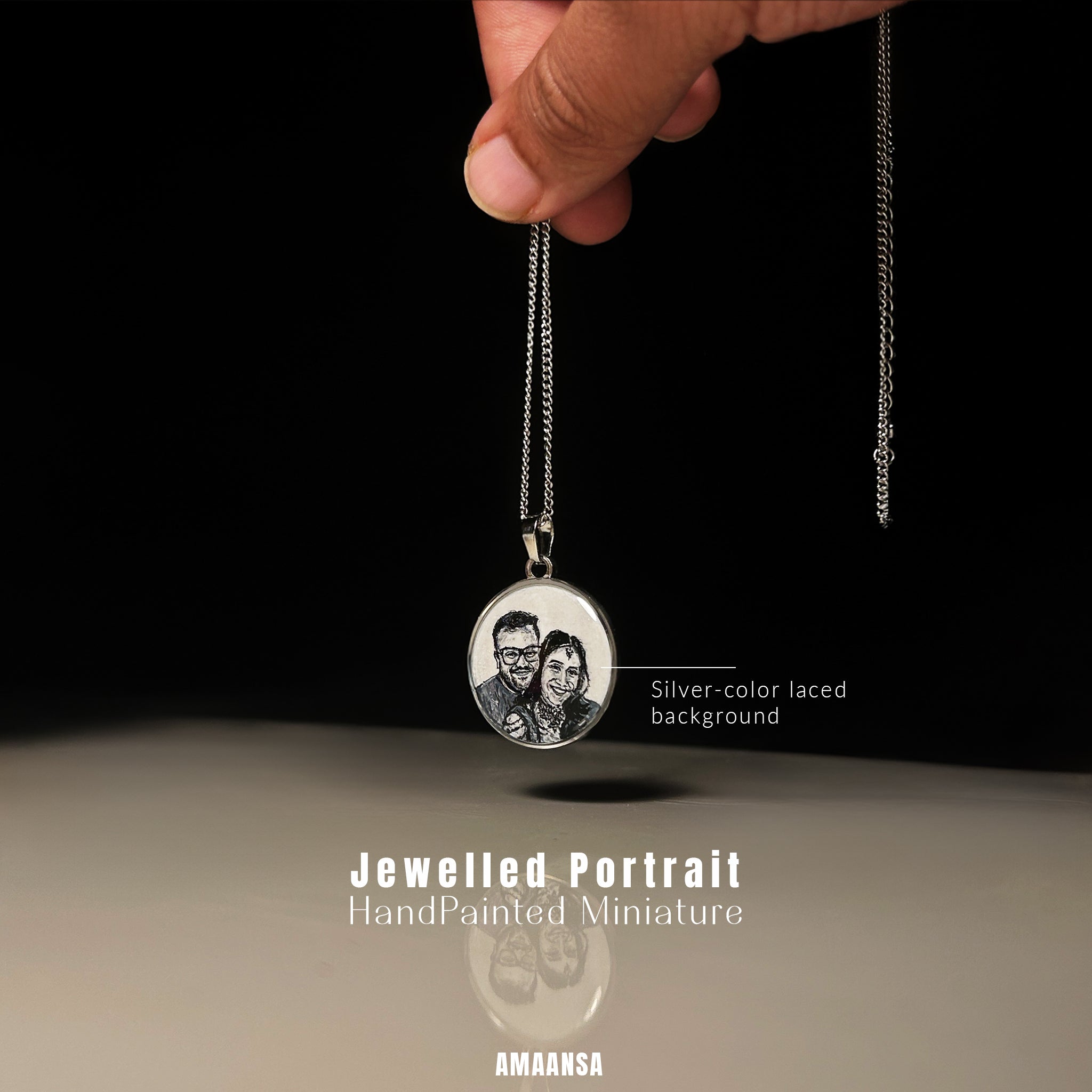 Jewelled portrait pendant with hand-painted miniature of a couple, held by a hand against a black background.