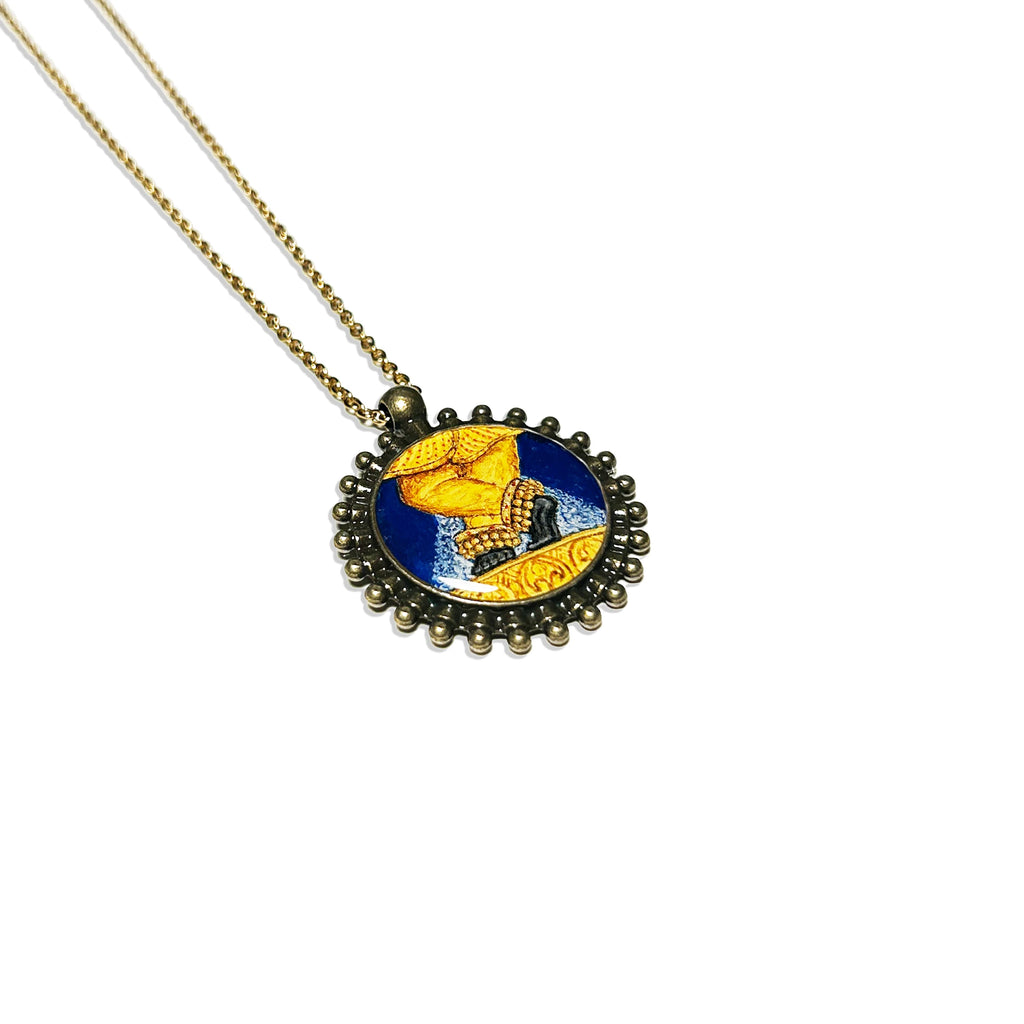 Vintage‑style Sri Radharamanji paduka pendant with hand‑painted feet on deep blue background, antique brass‑tone beaded frame on chain.

