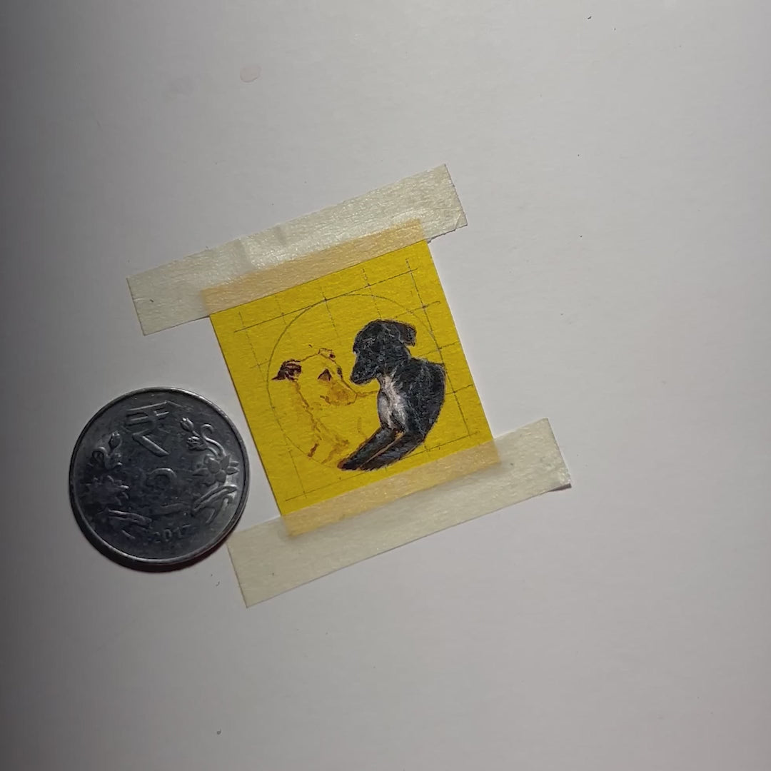 25-second behind-the-scenes video showcasing intimate miniature creation: artist meticulously painting pair of beloved dogs - golden and black-coated companions, each face smaller than artist's fingernail. One-rupee coin placed alongside highlights remarkably small scale, where finest brush strokes bring out detailed expressions on naples yellow canvas. Portrait destined for artisan pendant, demonstrates extraordinary precision where each pet's features occupy mere millimeters.