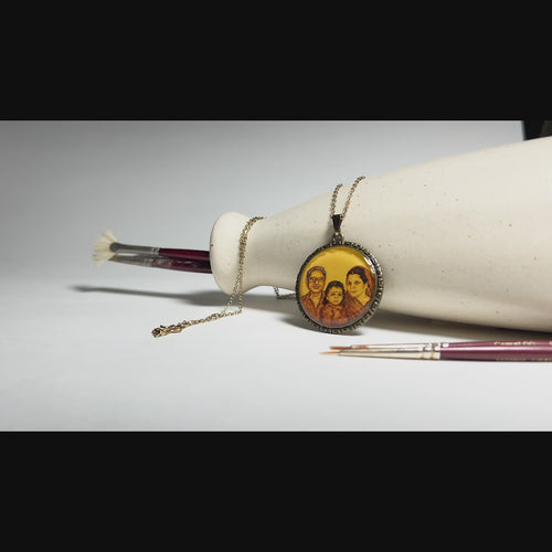 8 sec video : AMAANSA's artisan three-portrait pendant (32mm), weaving a family legacy through miniature art. A touching trio of grandfather, grandchild, and grandmother painted with heritage-inspired hues. Elegant Greek Key pattern bordering this generational story. Showcased against pristine white backdrop with artist's brushes, rotating gracefully to reveal intricate details as ambient music plays. Sealed with luminous protective layer, this wearable heirloom celebrates family connections.