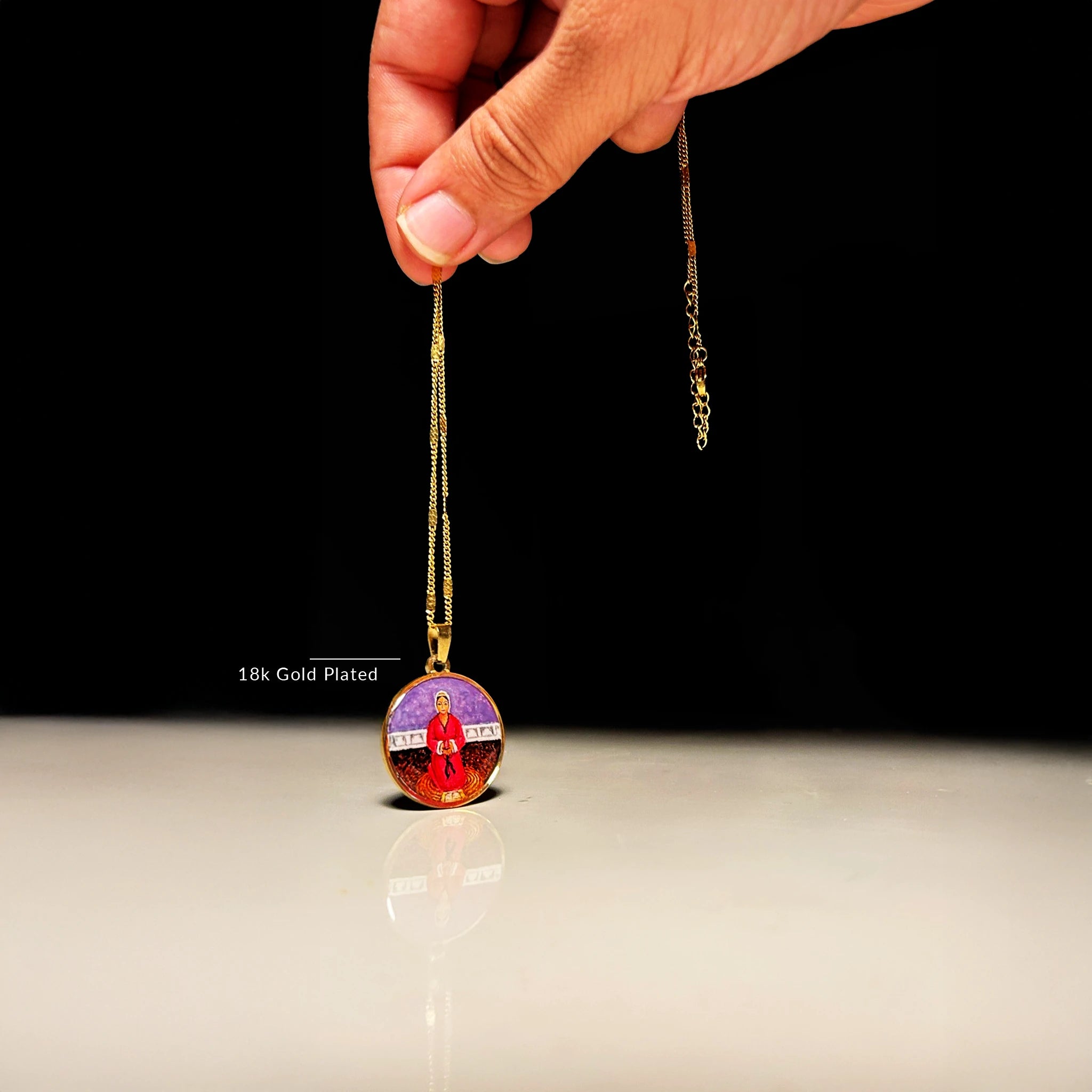 Hand‑painted Mata Rupa Bhawani miniature pendant on 18k gold‑plated chain, devotional jewelry lifted against dark studio background.