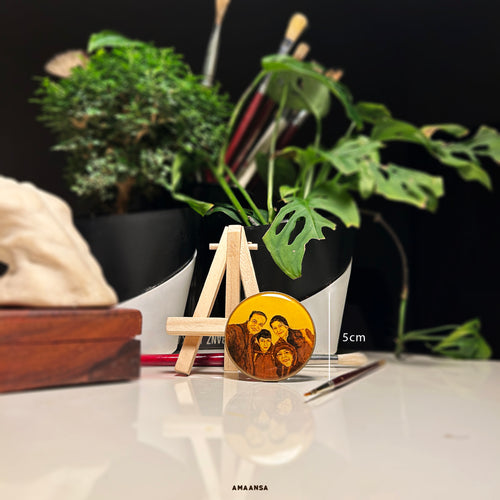 Hand-painted miniature of a family of four—father, mother, and two children—posing in a warm, candid, selfie-style portrait. Displayed as a tabletop showpiece on a wooden easel with vintage hues. Perfect for custom family portraits. size is 5cm diamtere. Painting is protected by metal base from the back and resin coating from the front.