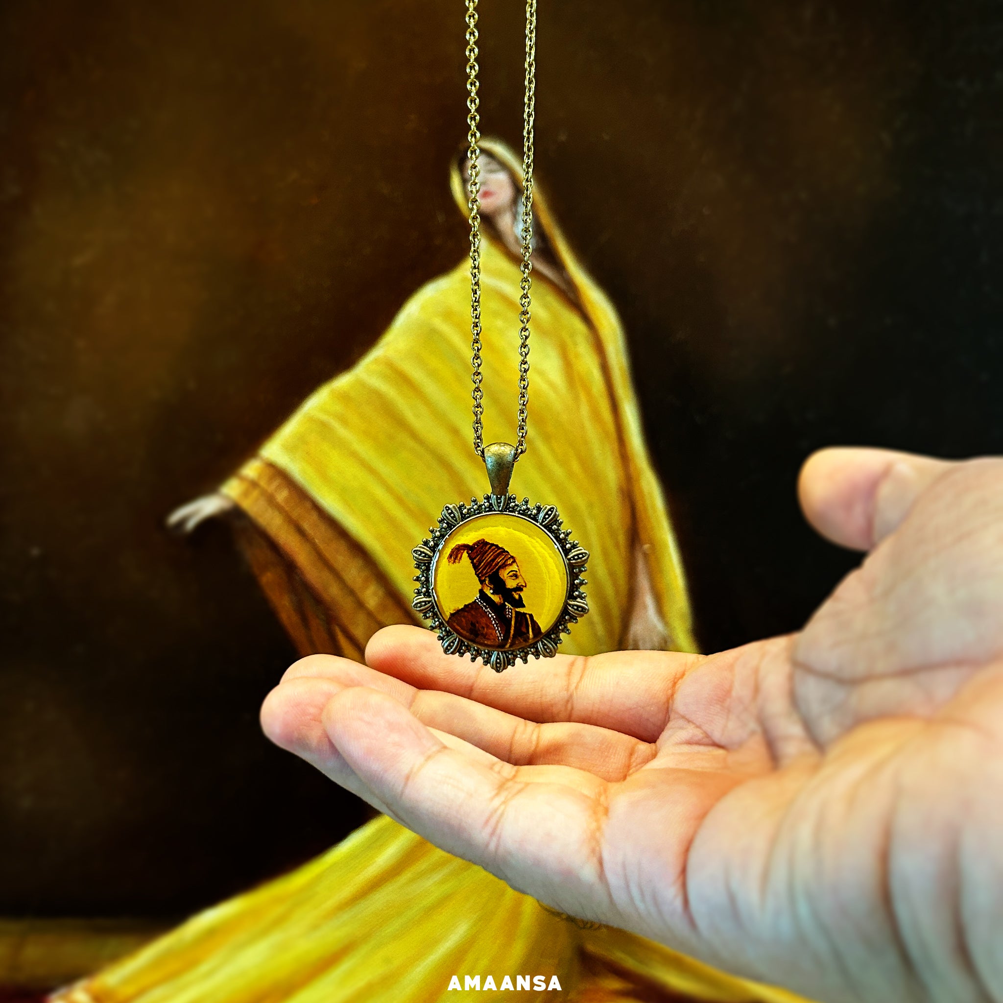 This handcrafted pendant from AMAANSA Fine Arts Studio’s 'Artistry in Faith' collection captures the chest-length portrait of Chhatrapati Shivaji Maharaj. His side profile is painted with precise detail, showing his turban decorated with white beads (moti) and traditional attire. Set within a small circle, the painting is surrounded by an ornate metal frame, making it a unique piece of wearable art. The pendant includes a chain and is perfect for honoring the legacy of the Maratha warrior. 
