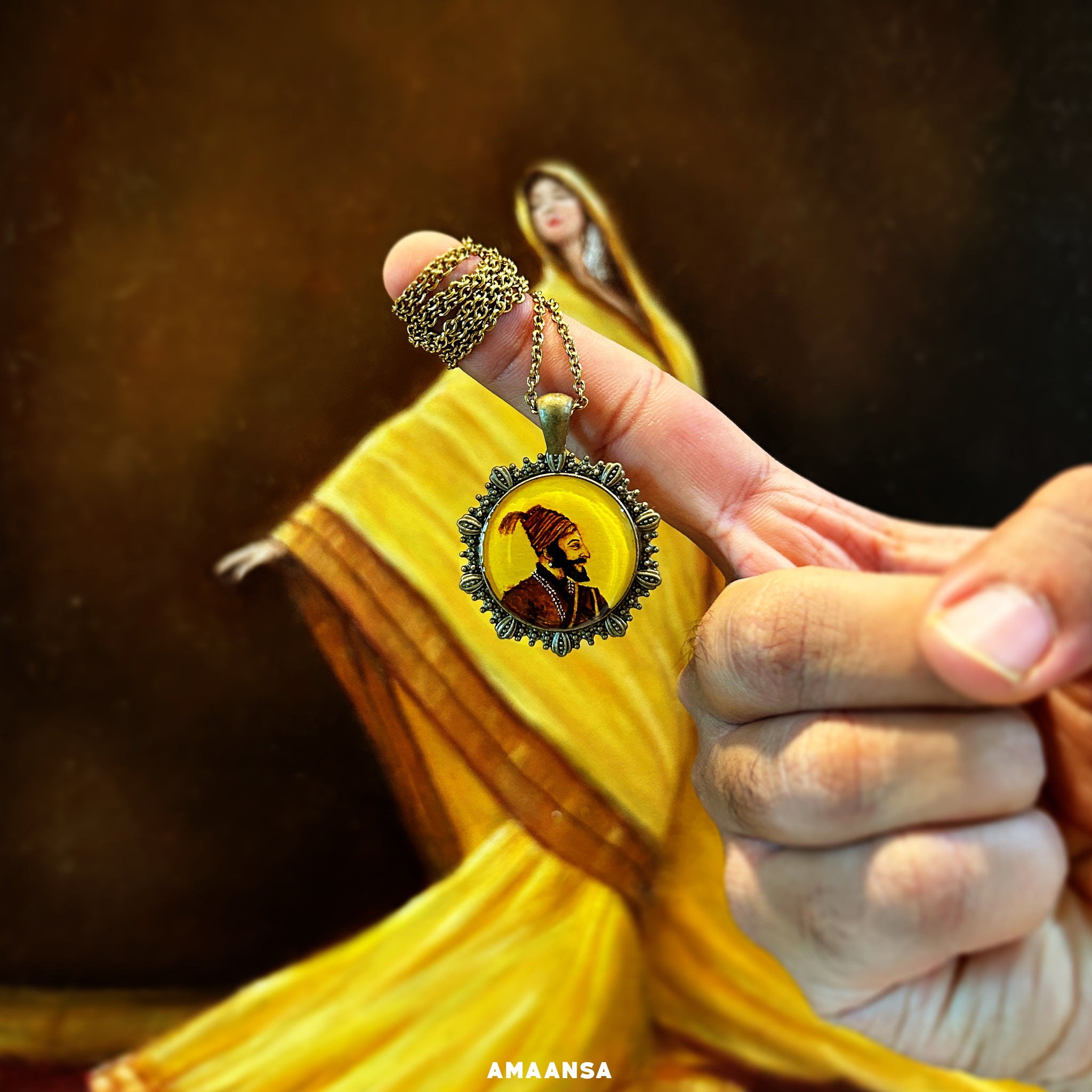 A miniature pendant from the 'Artistry in Faith' collection depicting Chhatrapati Shivaji Maharaj, the pride of the Marathas. The painting shows his iconic side profile, wearing a traditional turban adorned with white beads (moti) and detailed till his chest. The portrait, set against a yellow background, is housed in a vintage metal frame with intricate detailing. This wearable art piece, complete with a chain, highlights Shivaji Maharaj’s strength and legacy. It is protected by a metal base and resin