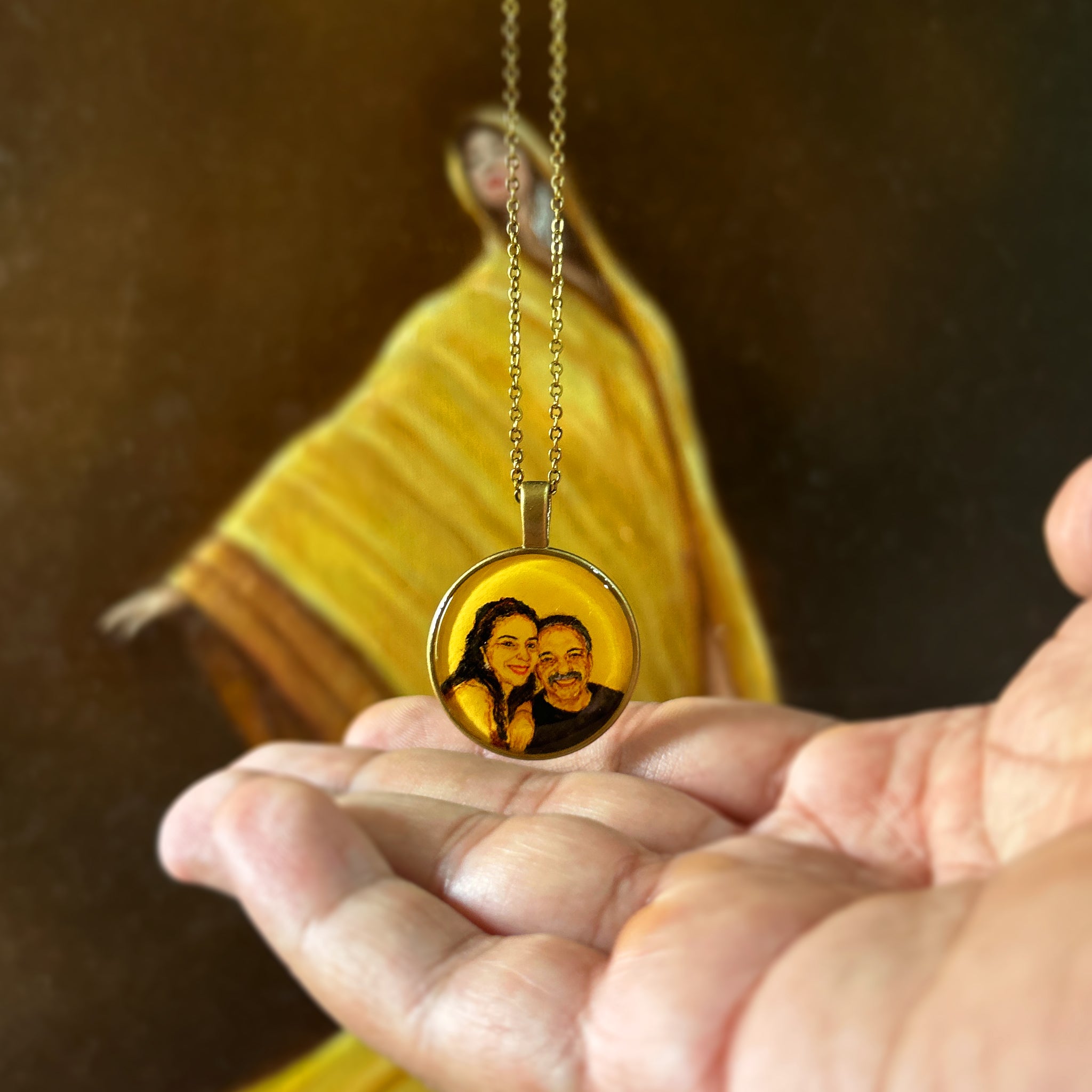 Thoughtfully rendered father-daughter portrait (26mm) bringing black and white memory to life: her radiant smile beside dad's gentle expression, painted with warmth against naples yellow lending vintage charm. Pendant rests gently in open palm, antique gold colored chain suspended against artist's oil painting with billowing sari, each detail preserved as luminous birthday gift creating Mumbai-Mumbai bridge through cherished memories.