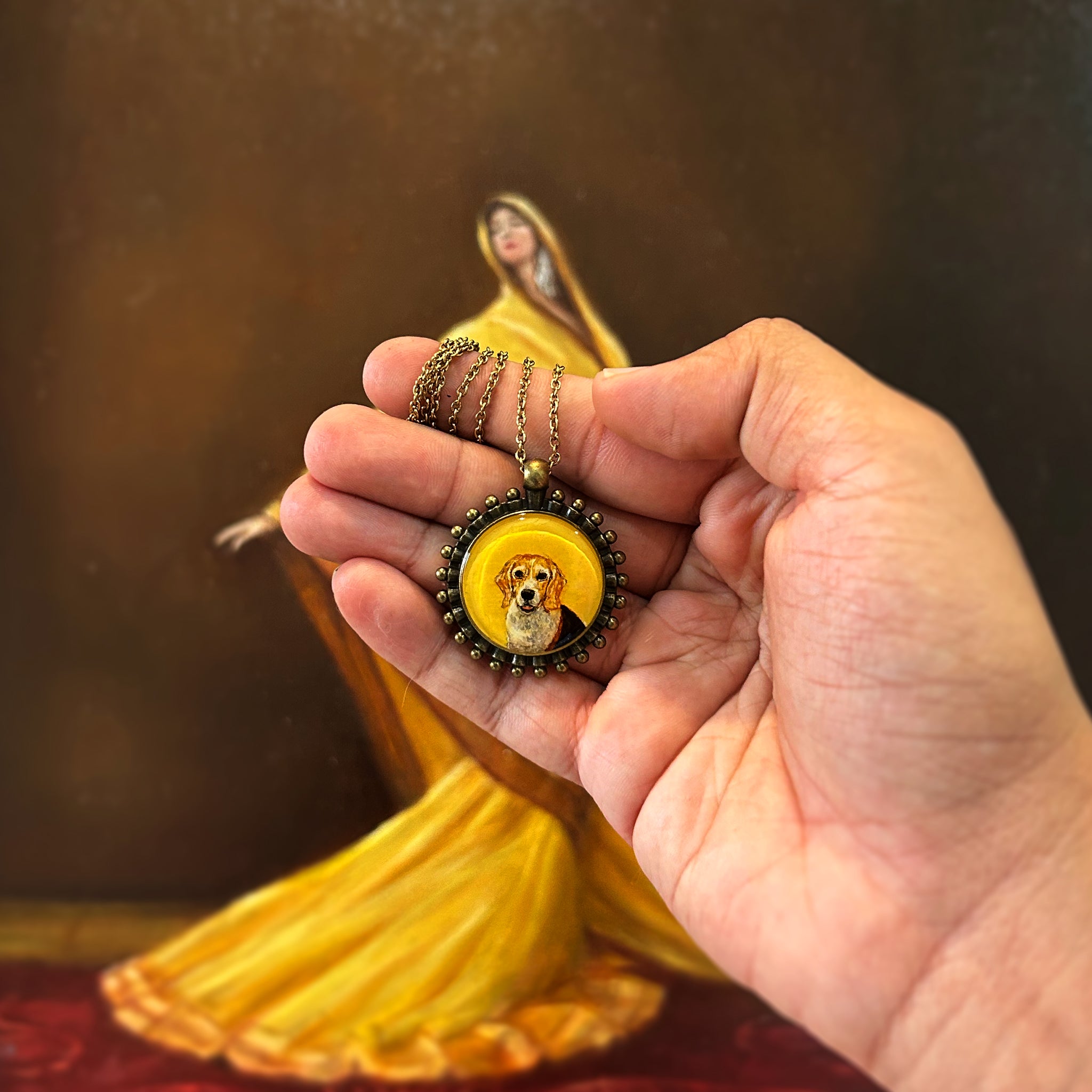 Artistically rendered diminutive portrait (26mm) featuring faithful Beagle dog sweet expression, adorned with vintage-inspired Pathakkam Moti beaded frame. Treasured memory piece rests in open palm with antique gold chain gracefully coiled, photographed against ethereal yellow-draped figure creating dramatic amber ambiance. Each precious detail, from bright eyes to soft muzzle, preserved with artisan-grade finish in this forever keepsake.