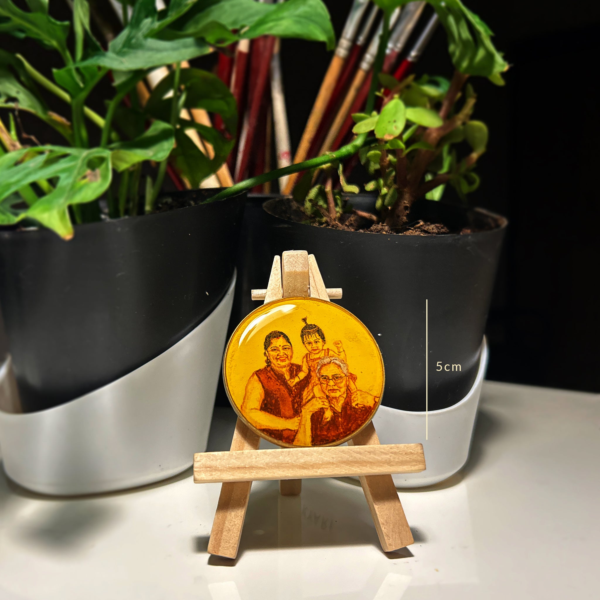 Hand-painted tabletop miniature (5cm) showcasing multigenerational bond: grandfather tenderly balancing energetic granddaughter on shoulders, her playful topknot visible, while mother's radiant smile completes the scene, all painted in warm sepia tones on naples yellow background. Size measurement clearly displayed alongside artwork on wooden easel, nestled between modern planters with vibrant monstera leaves, demonstrating this cherished heirloom's perfect scale as intimate decor.