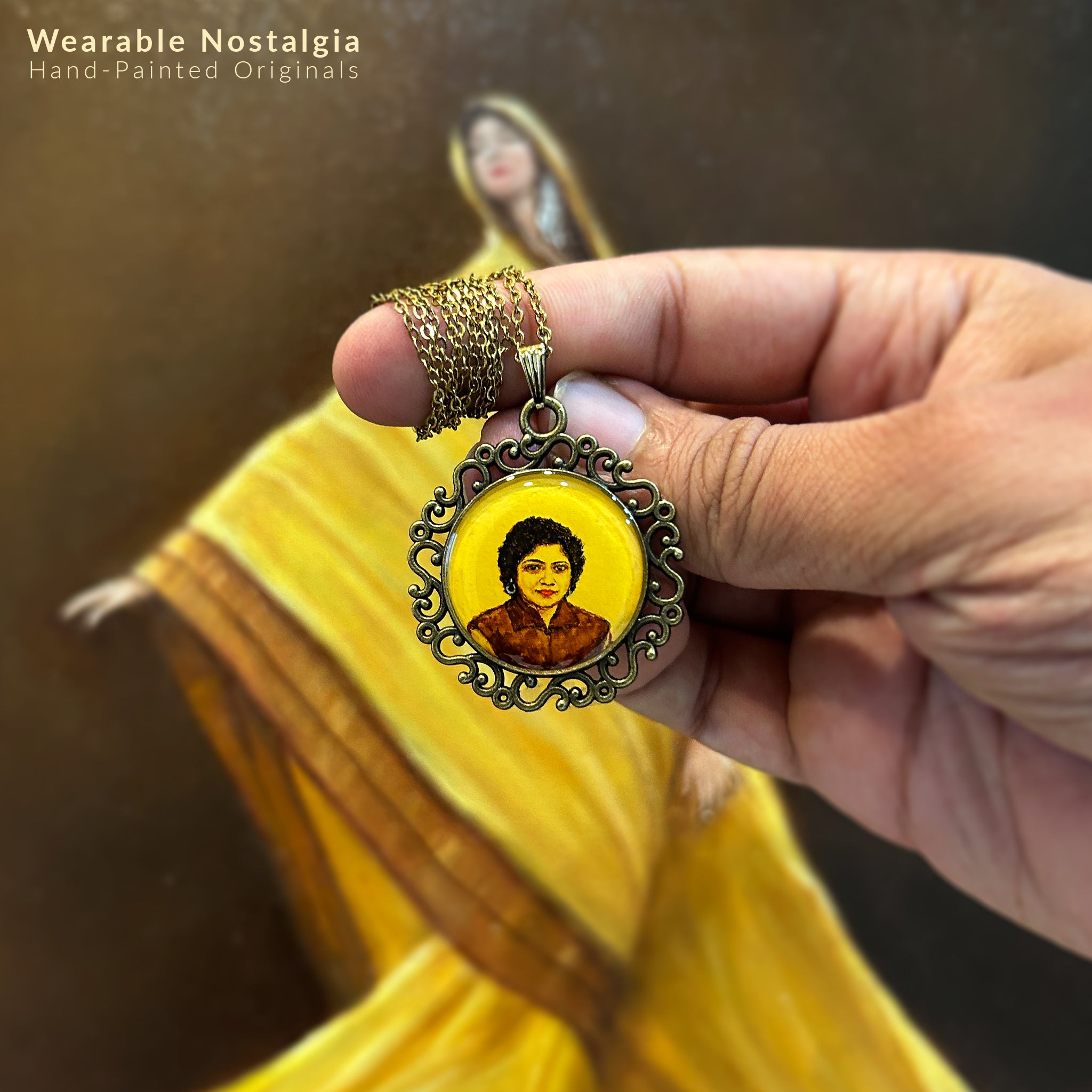 AMAANSA's bespoke portrait keepsake (26mm), reviving a treasured 1980s photograph of mother's youthful charm. Her confident smile and distinctive curls captured in rich brown tones with timeless elegance. Encased in our signature Victorian Scroll Border in antique brass finish. Chain artfully coiled around finger with pendant suspended gracefully in palm, set against artist's oil painting featuring yellow sari. Protected by crystal-clear sealant, this wearable art piece preserves cherished memories.