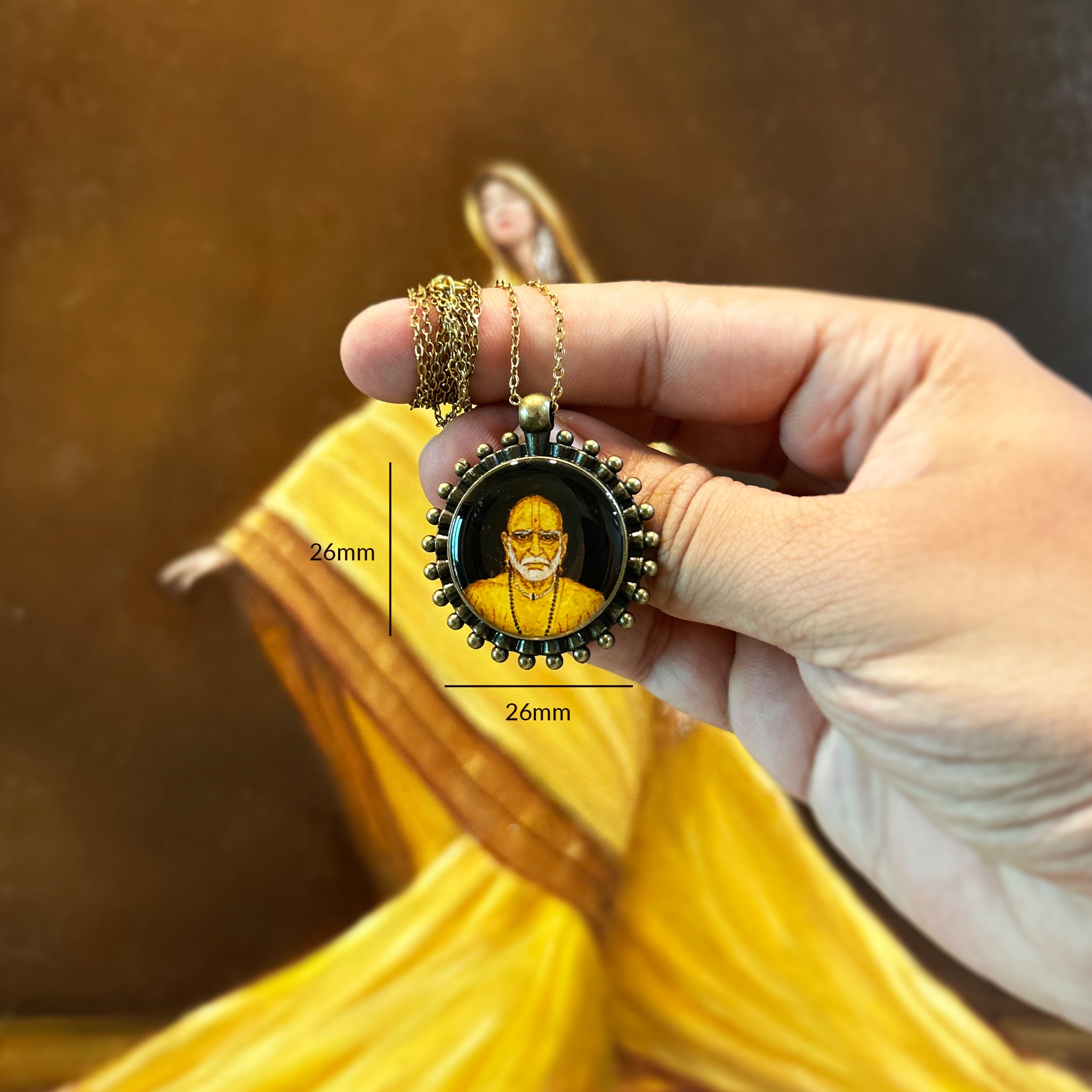 AMAANSA's sacred miniature pendant (26mm), capturing the divine presence of Swami Samartha in exquisite detail. His penetrating gaze and sacred tilak rendered with devotional precision, adorned by our signature Pearl Border (Pathakkam Moti) in antique brass finish. Antique gold colored chain delicately wrapped around finger with pendant displayed against artist's oil painting featuring ochre drapes. Protected by crystal-clear sealant, this spiritual keepsake offers constant divine companionship.