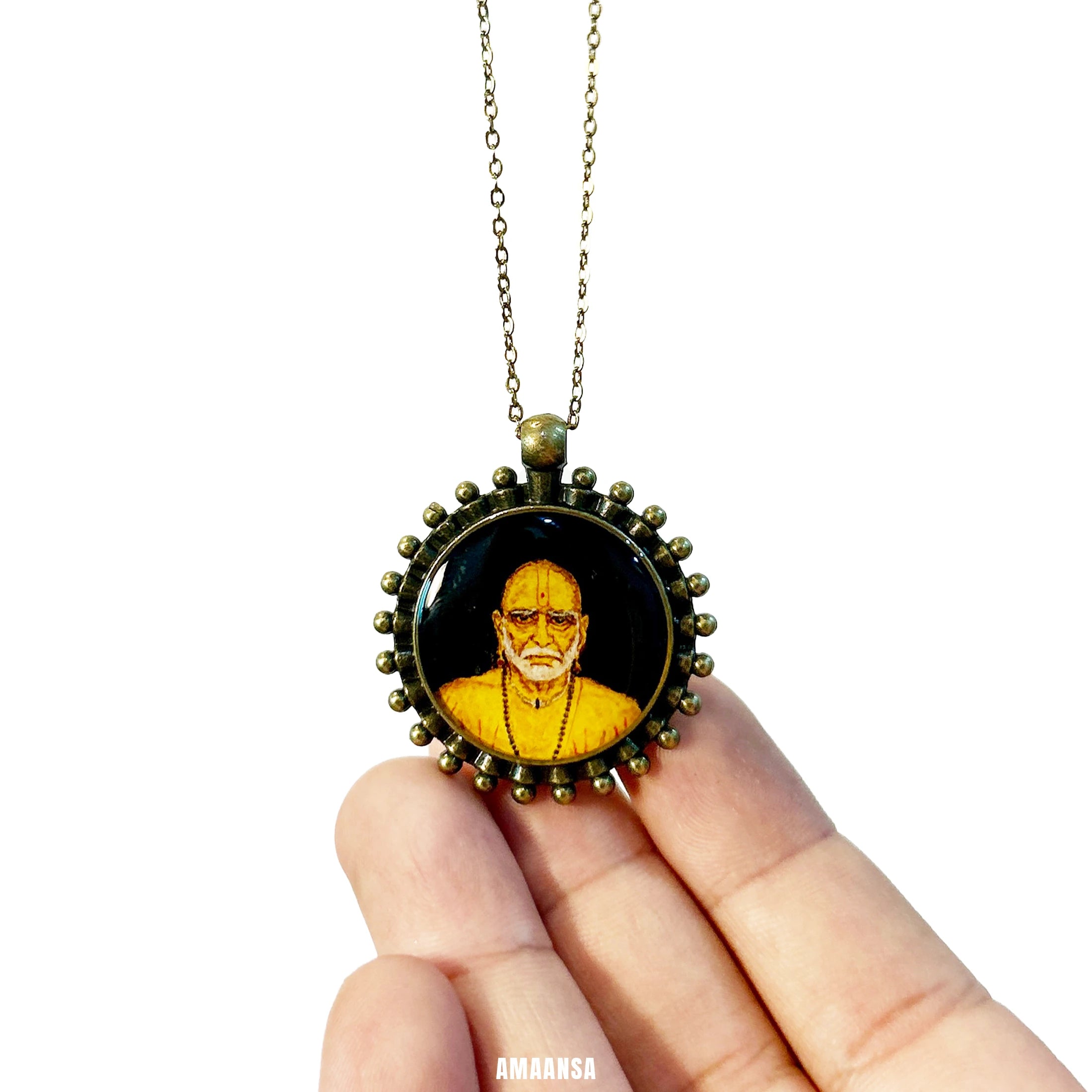 Necklace Round Swami Samarth portrait pendant resting on reflective surface, spiritual jewelry for devotees featuring a portrait on a white background