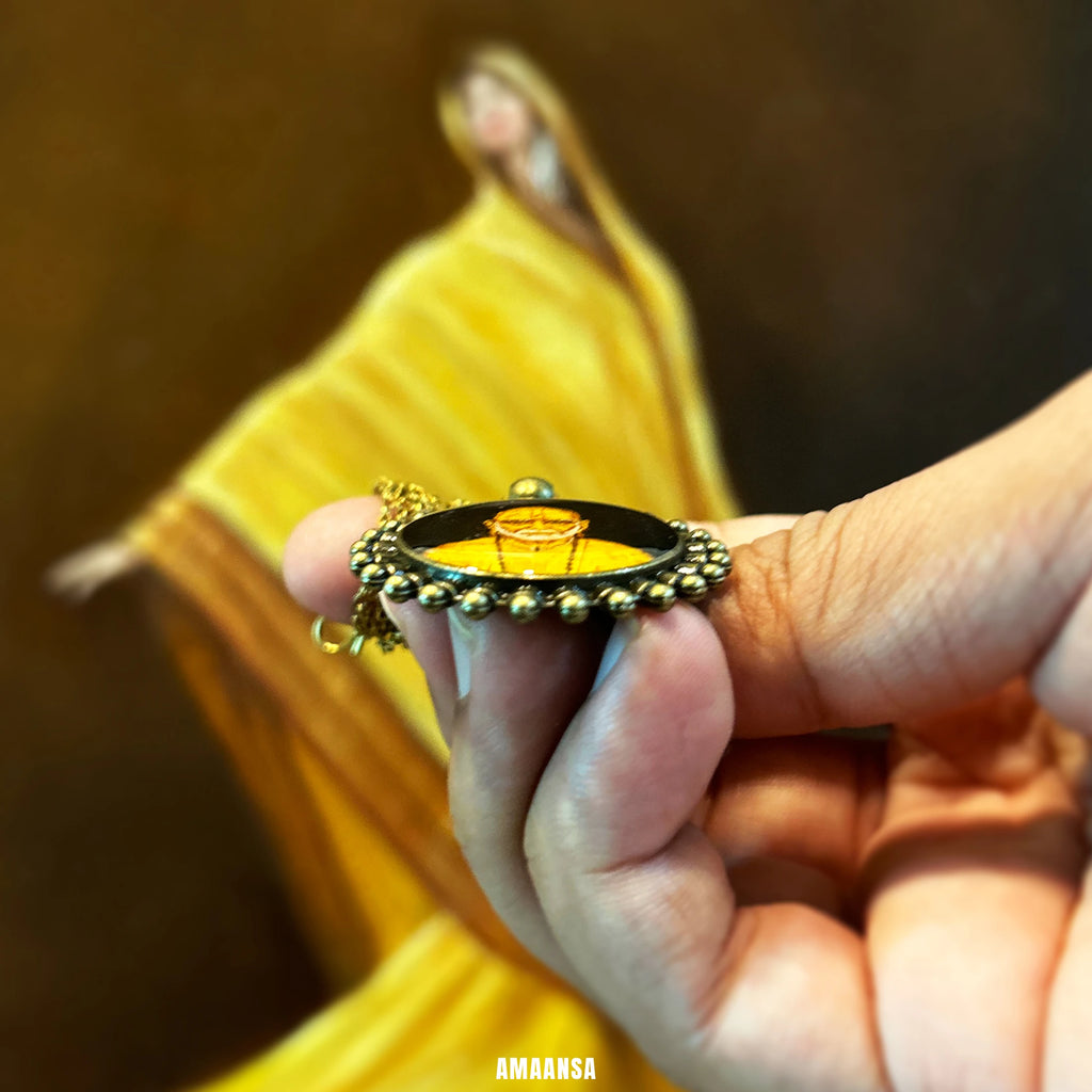 Hand holding a Side angle of Swami Samarth pendant on fingers against a blurred background