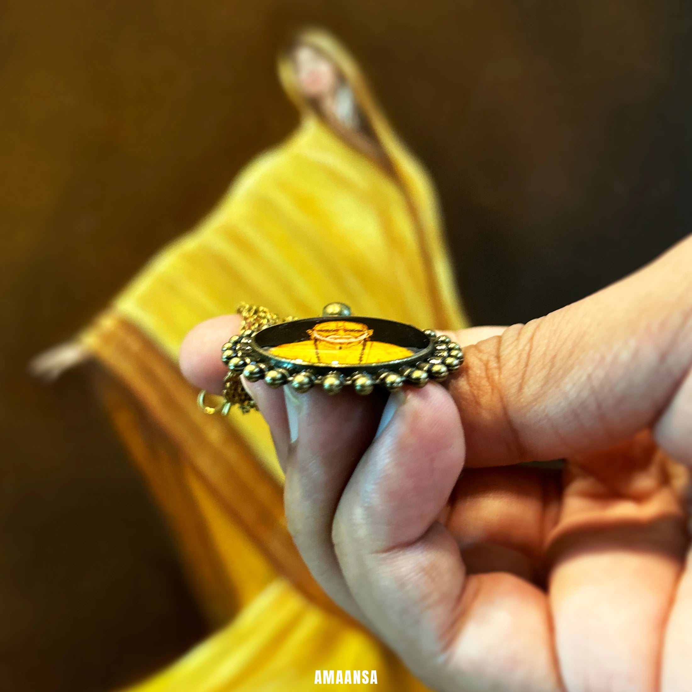 Hand holding a Side angle of Swami Samarth pendant on fingers against a blurred background